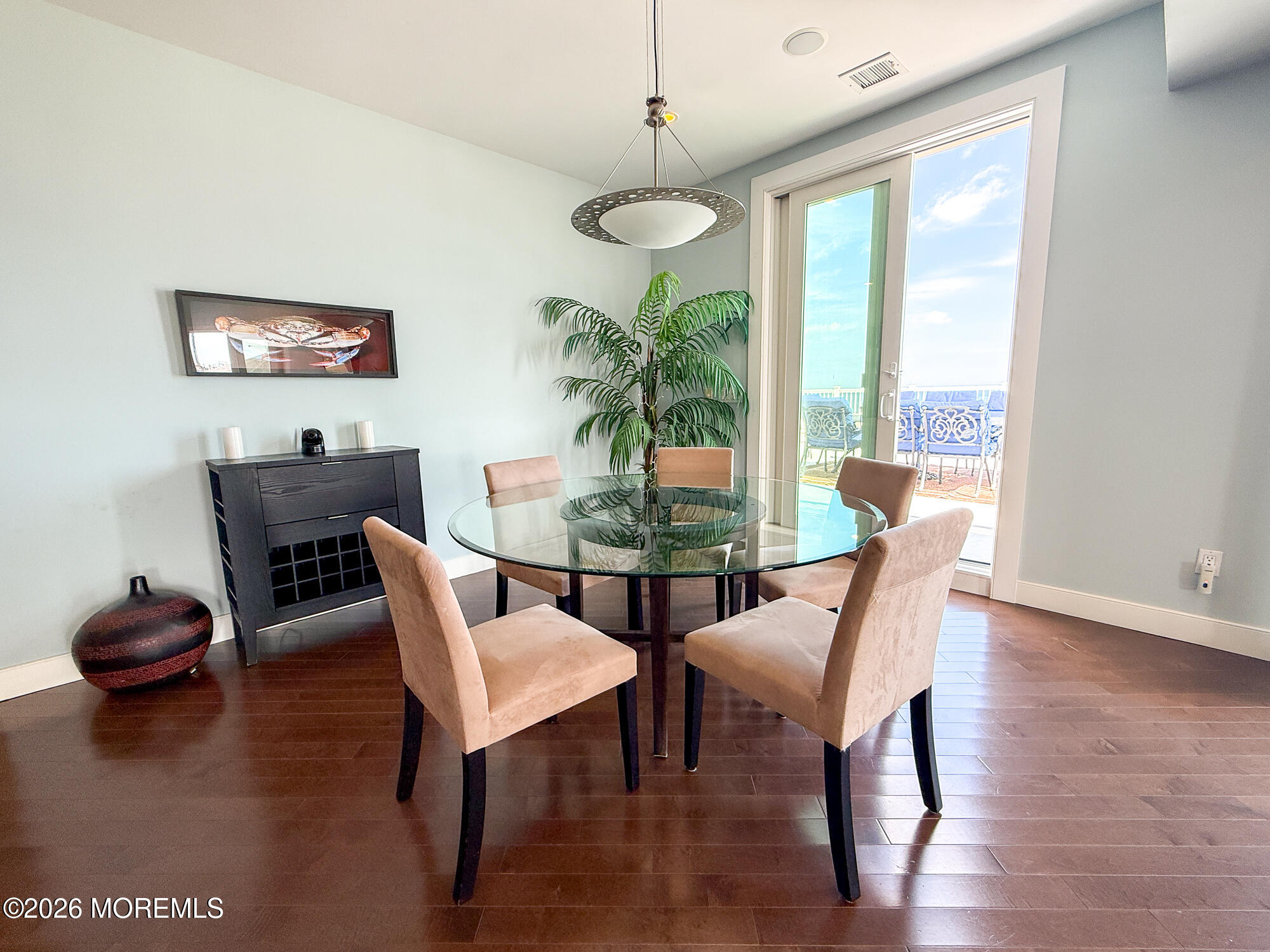 Dining room with a round glass table, beige chairs, and glass doors to a patio.