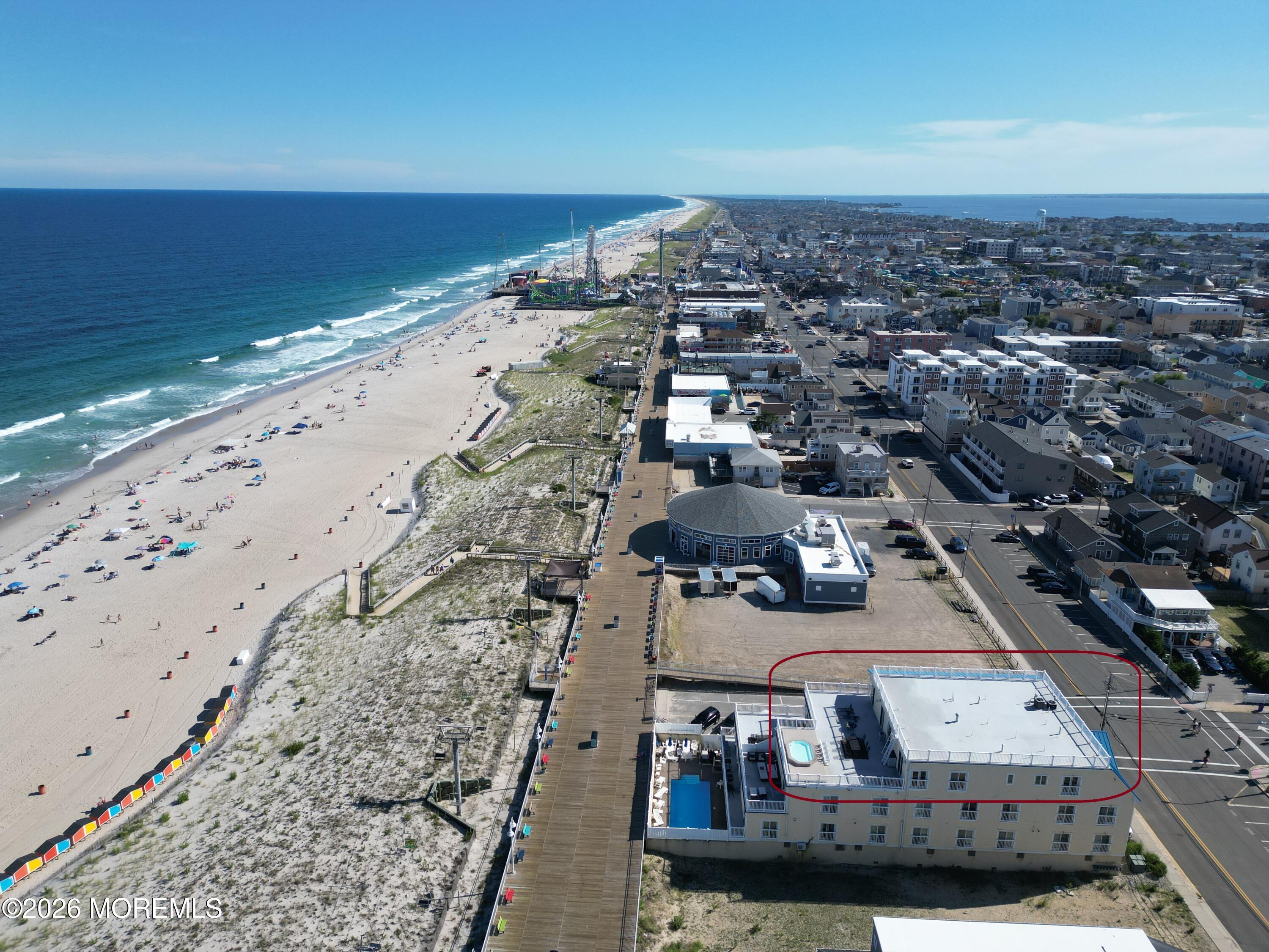 Aerial view of a beachfront building outlined in red beside the boardwalk and ocean.