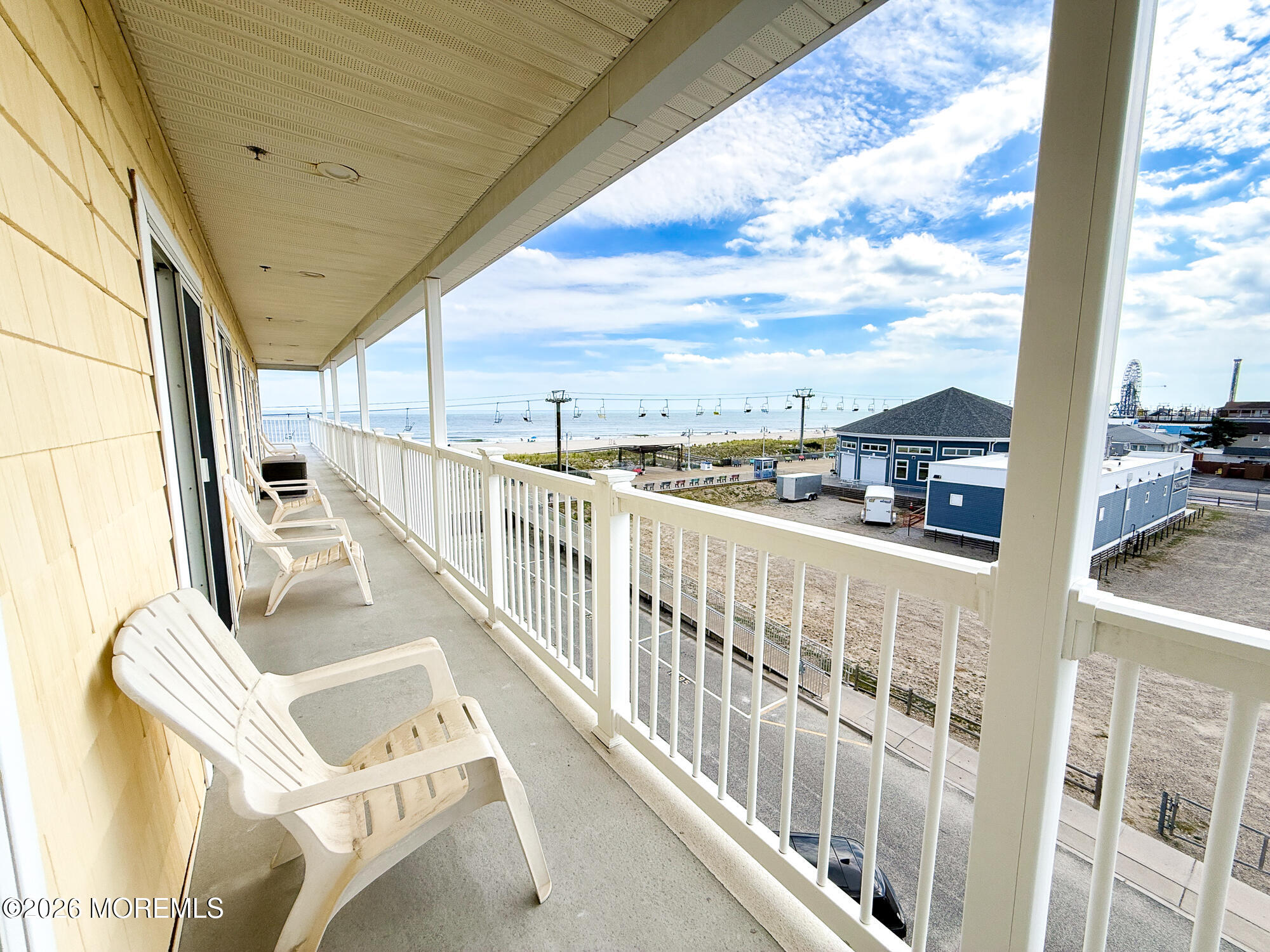 Covered balcony with lounge chairs overlooking the ocean and beach.