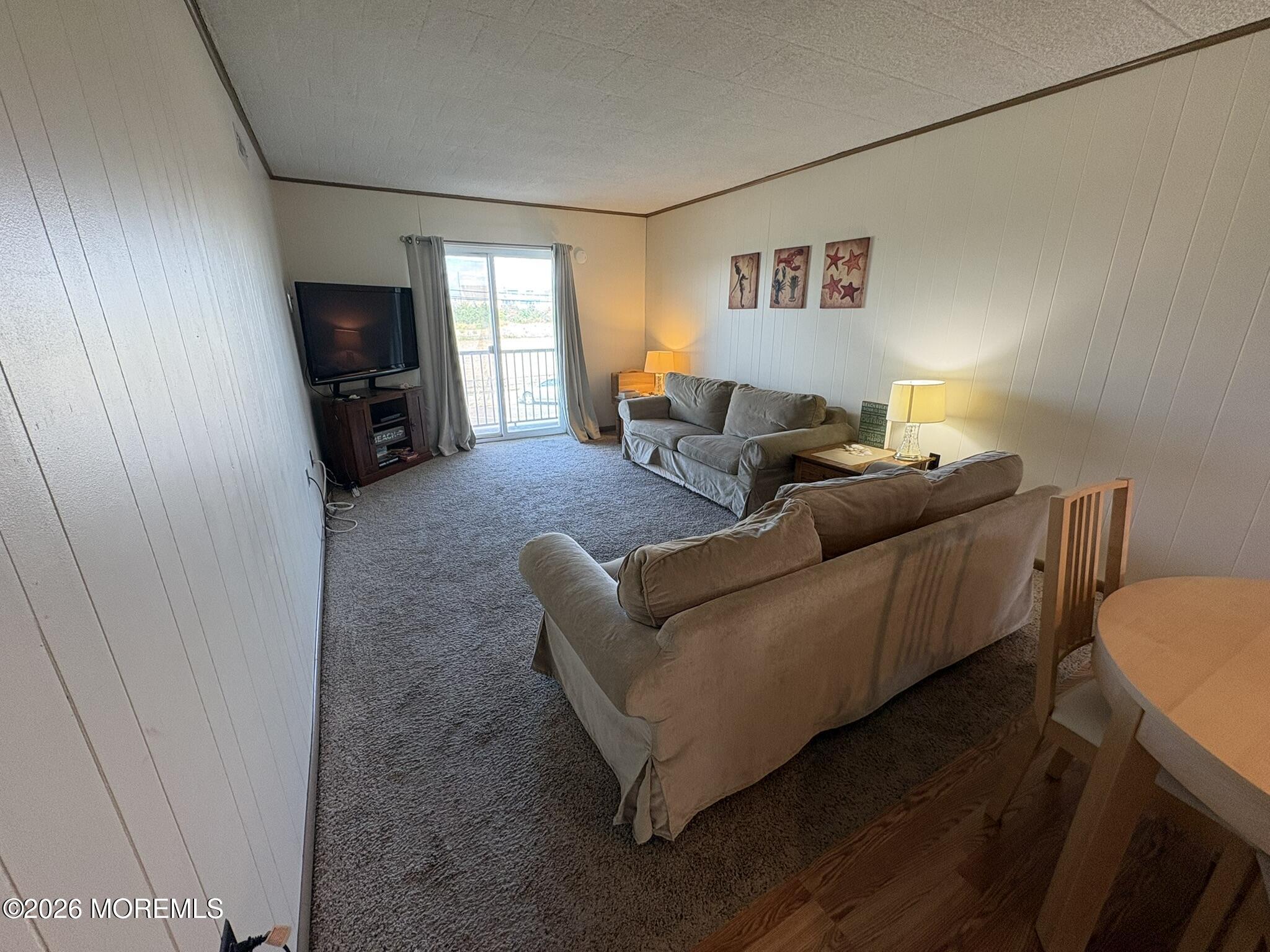 Furnished living room with gray sofas, carpet, and sliding glass doors.
