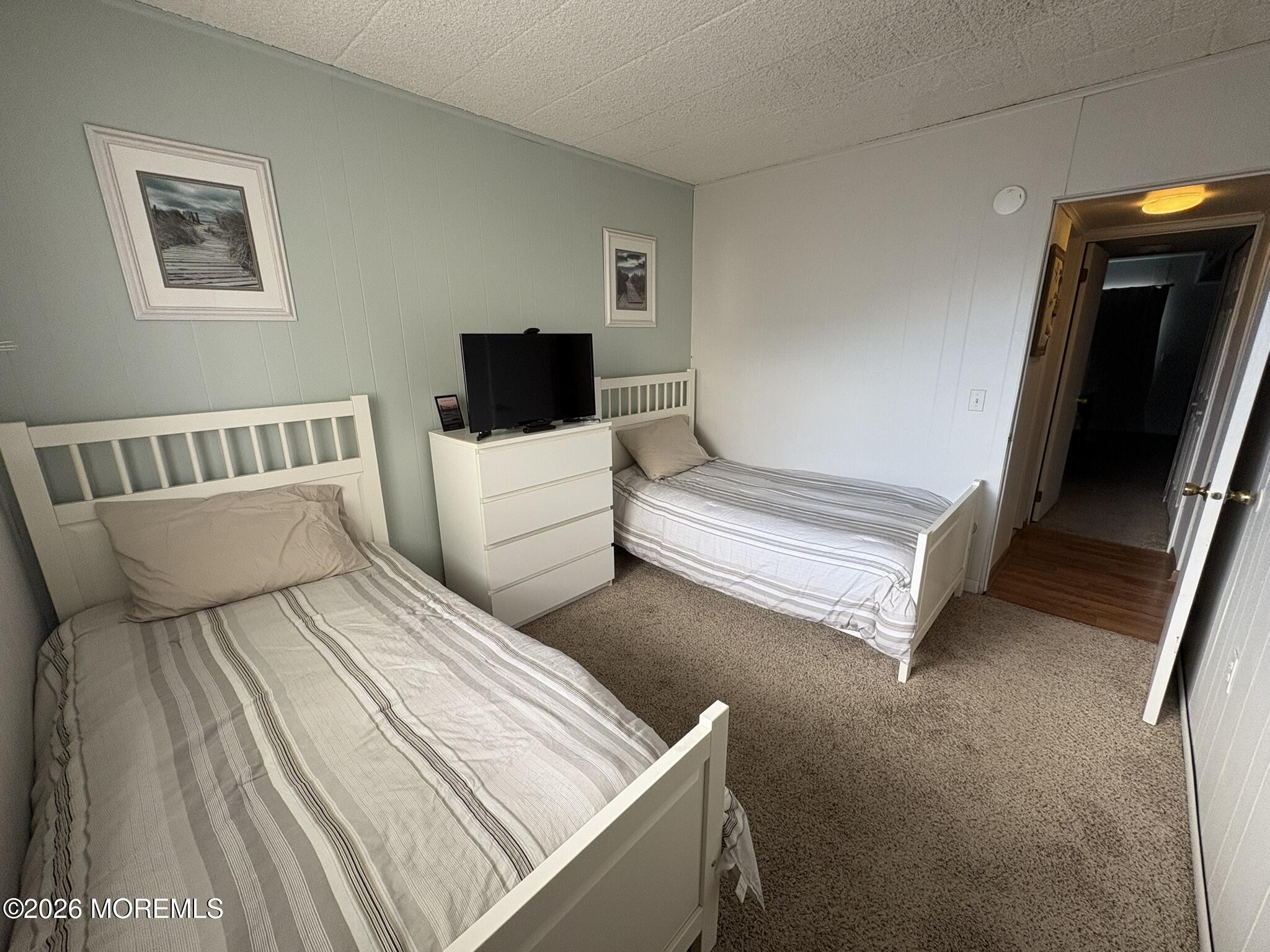 Bedroom with two twin beds, a dresser, and a television.
