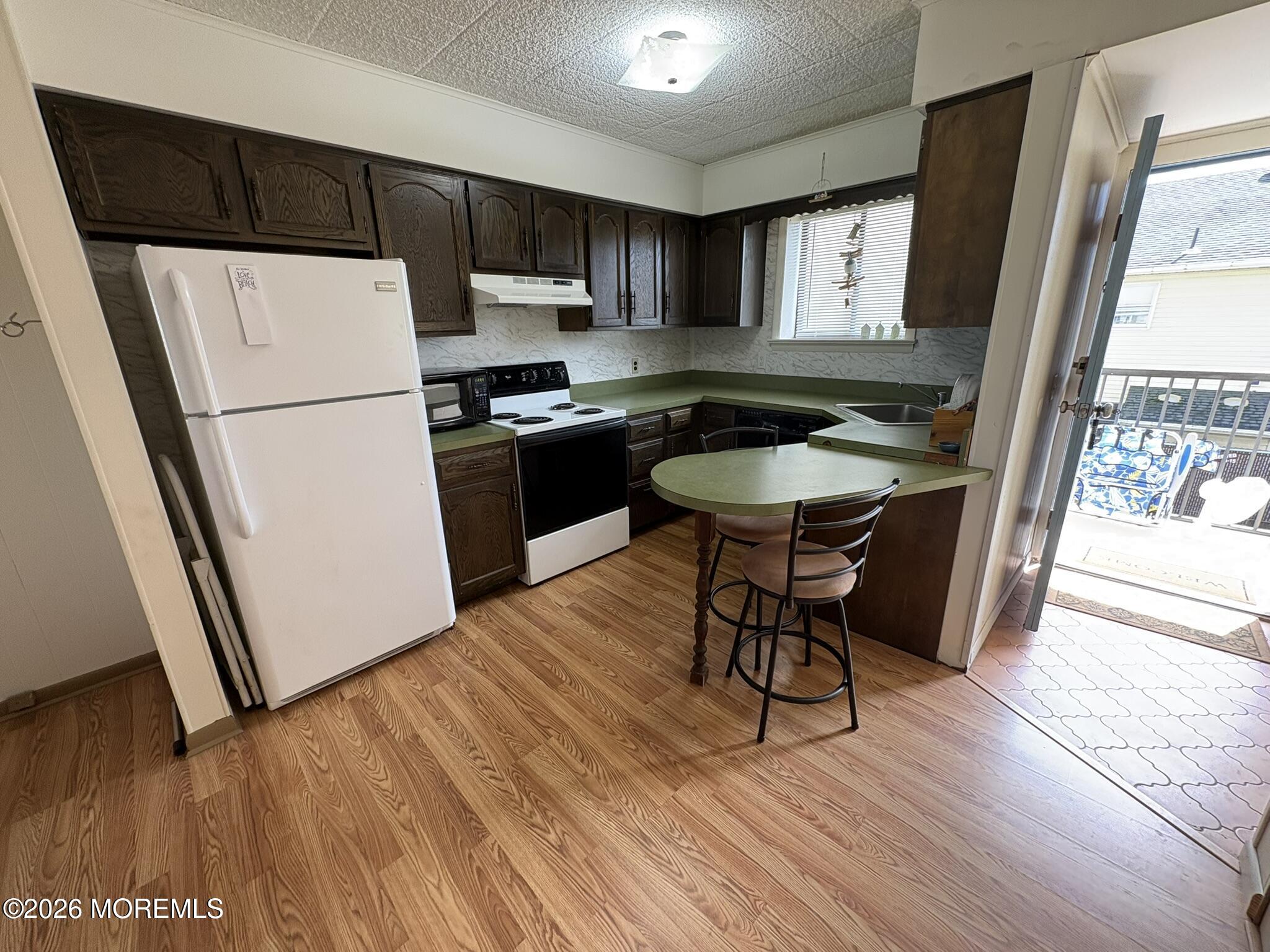 Kitchen with dark wood cabinets, green countertops, and an open door to the patio.