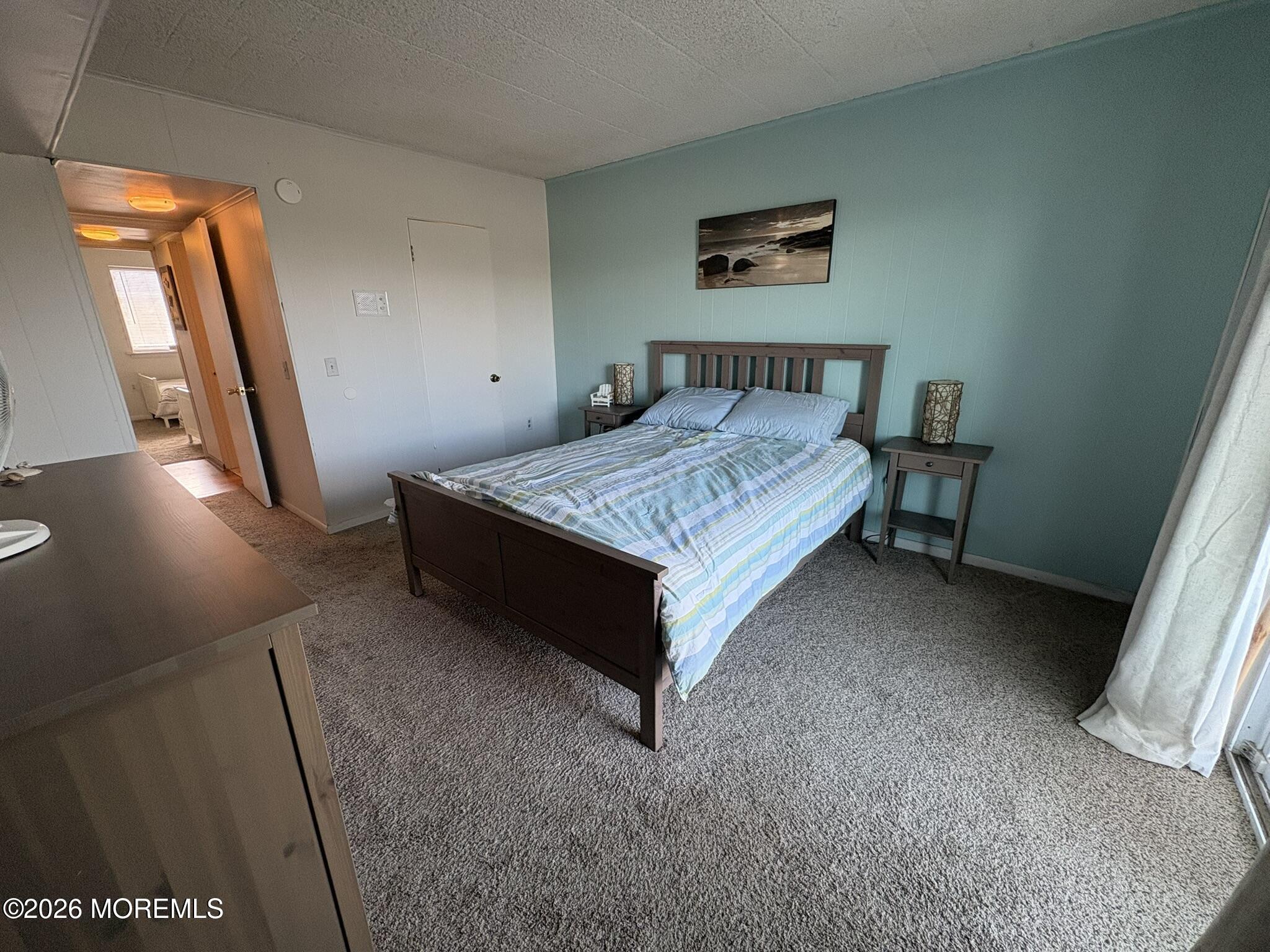 Bedroom with a dark wood bed, striped bedding, and a blue-green accent wall.