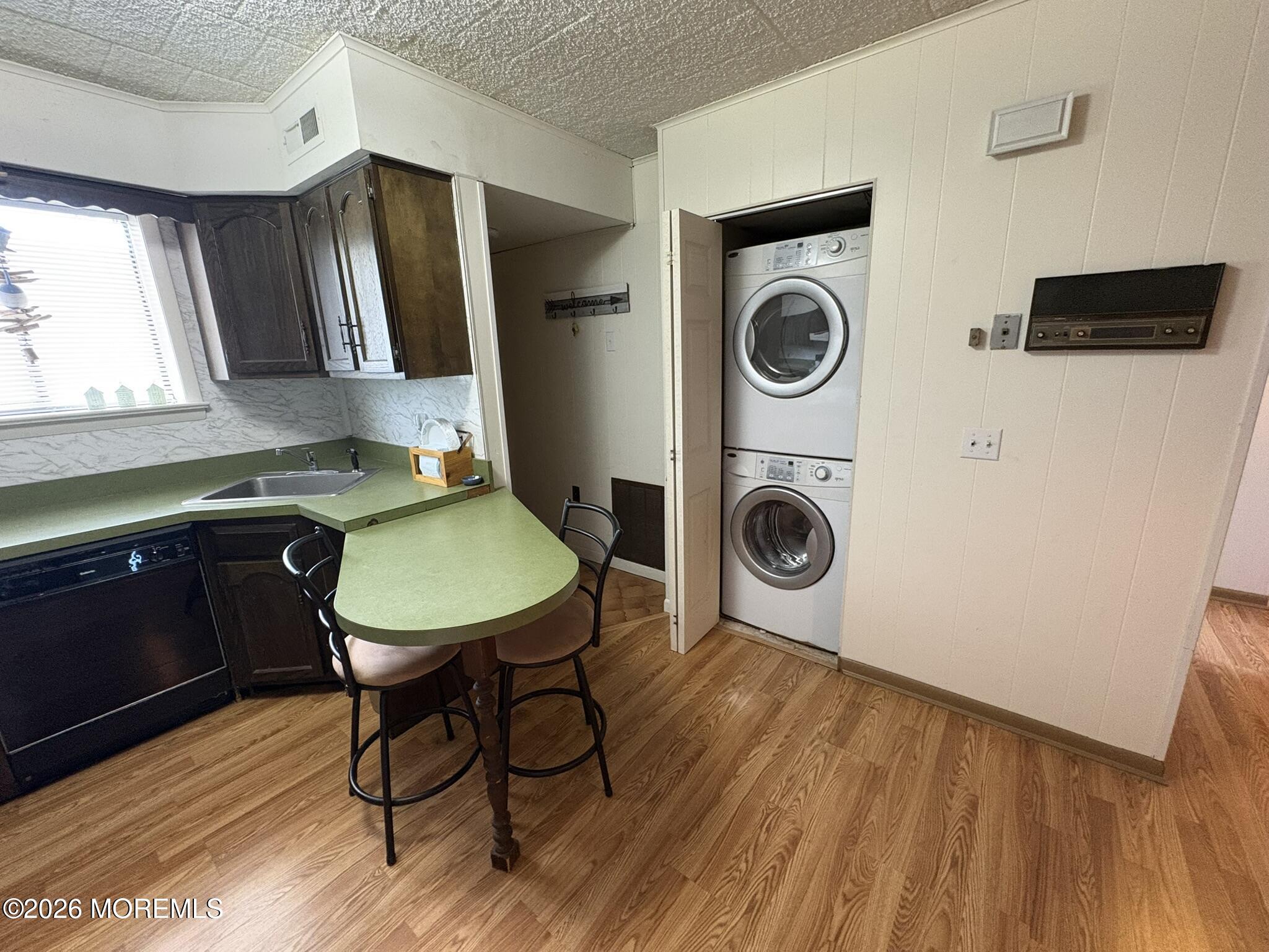 Kitchen with green countertops, a two-seat table, and stacked washer and dryer.