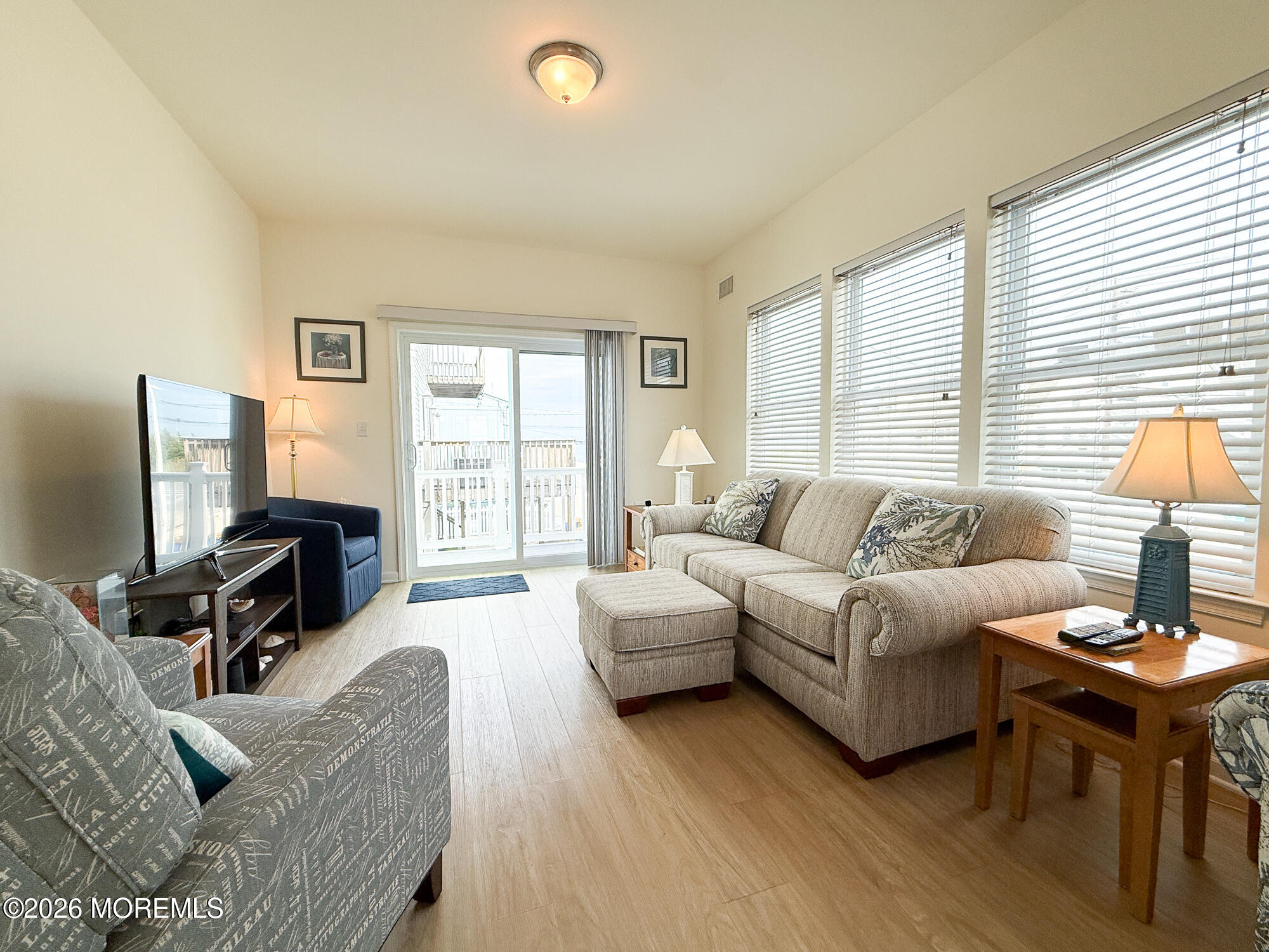 Living room with a beige sectional, patterned armchairs, and a sliding glass door to the deck.