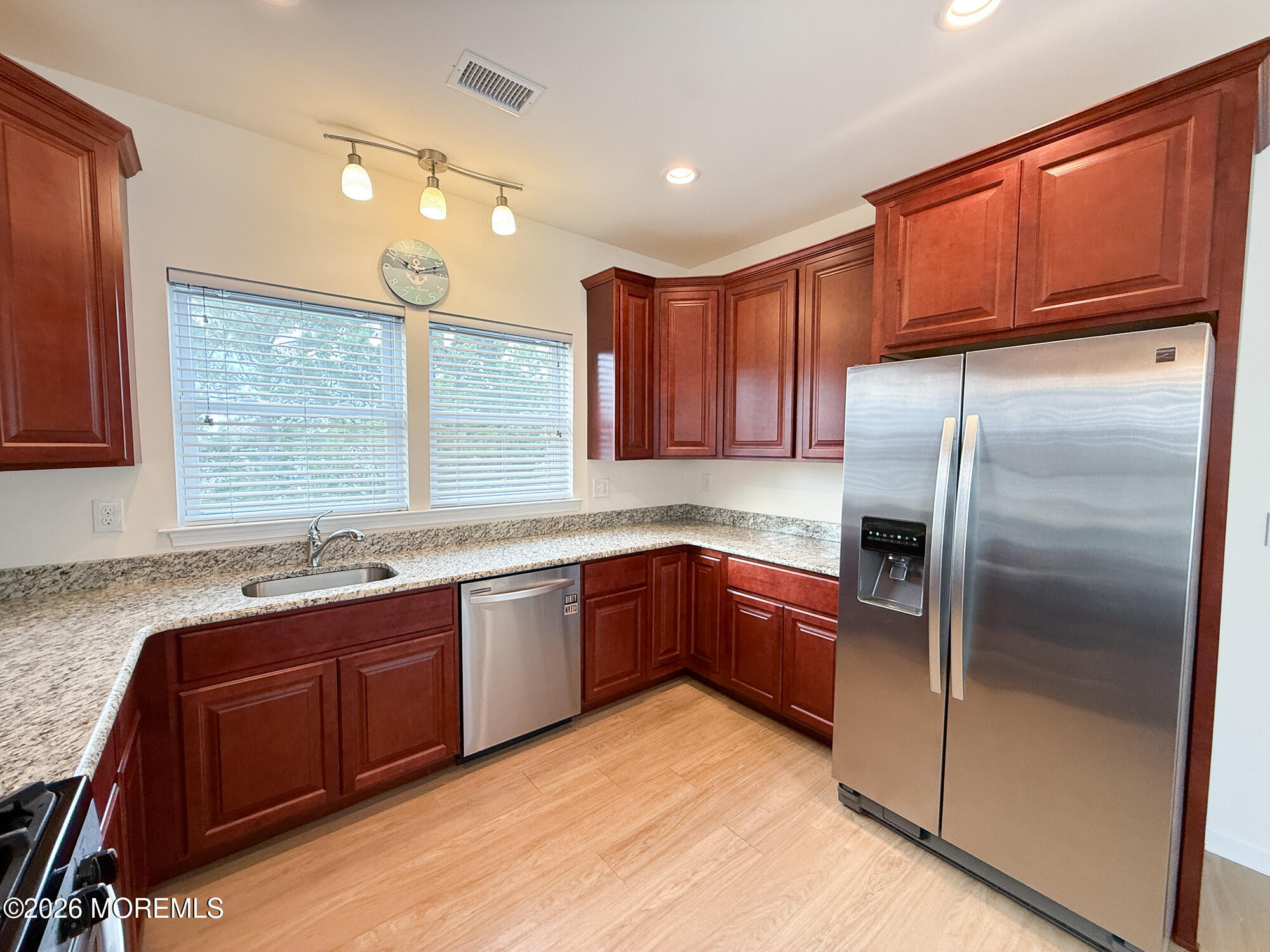 Kitchen with dark wood cabinets, granite counters, and stainless steel appliances.