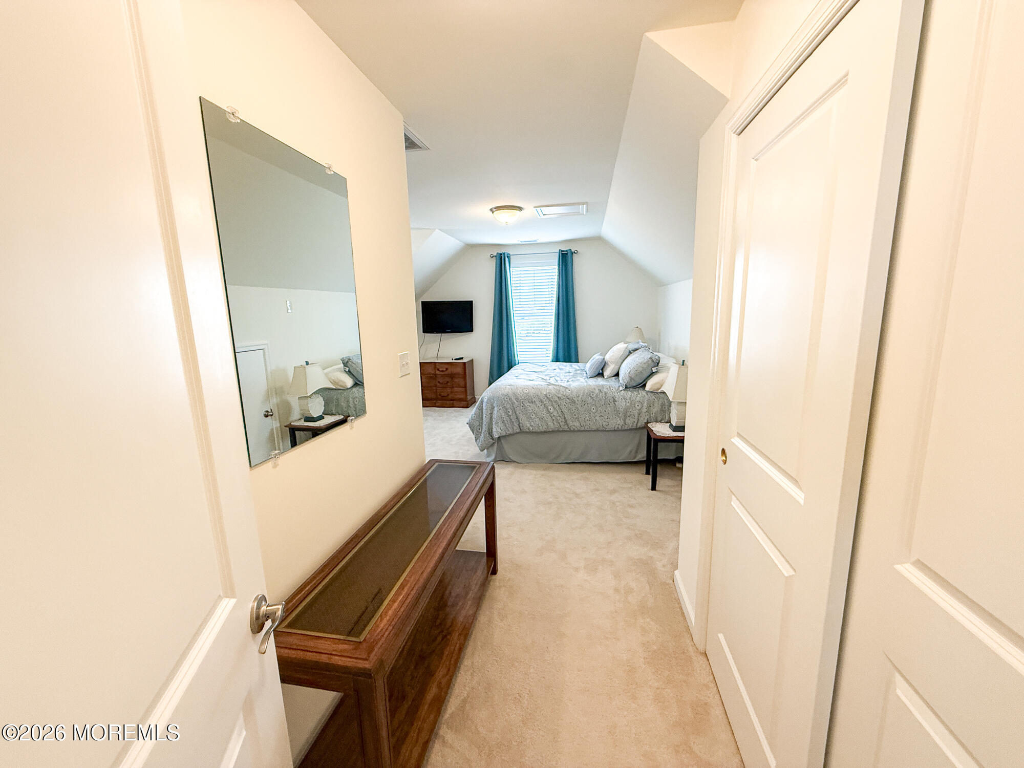 Furnished bedroom with a gray bed, teal curtains, and a sloped ceiling.