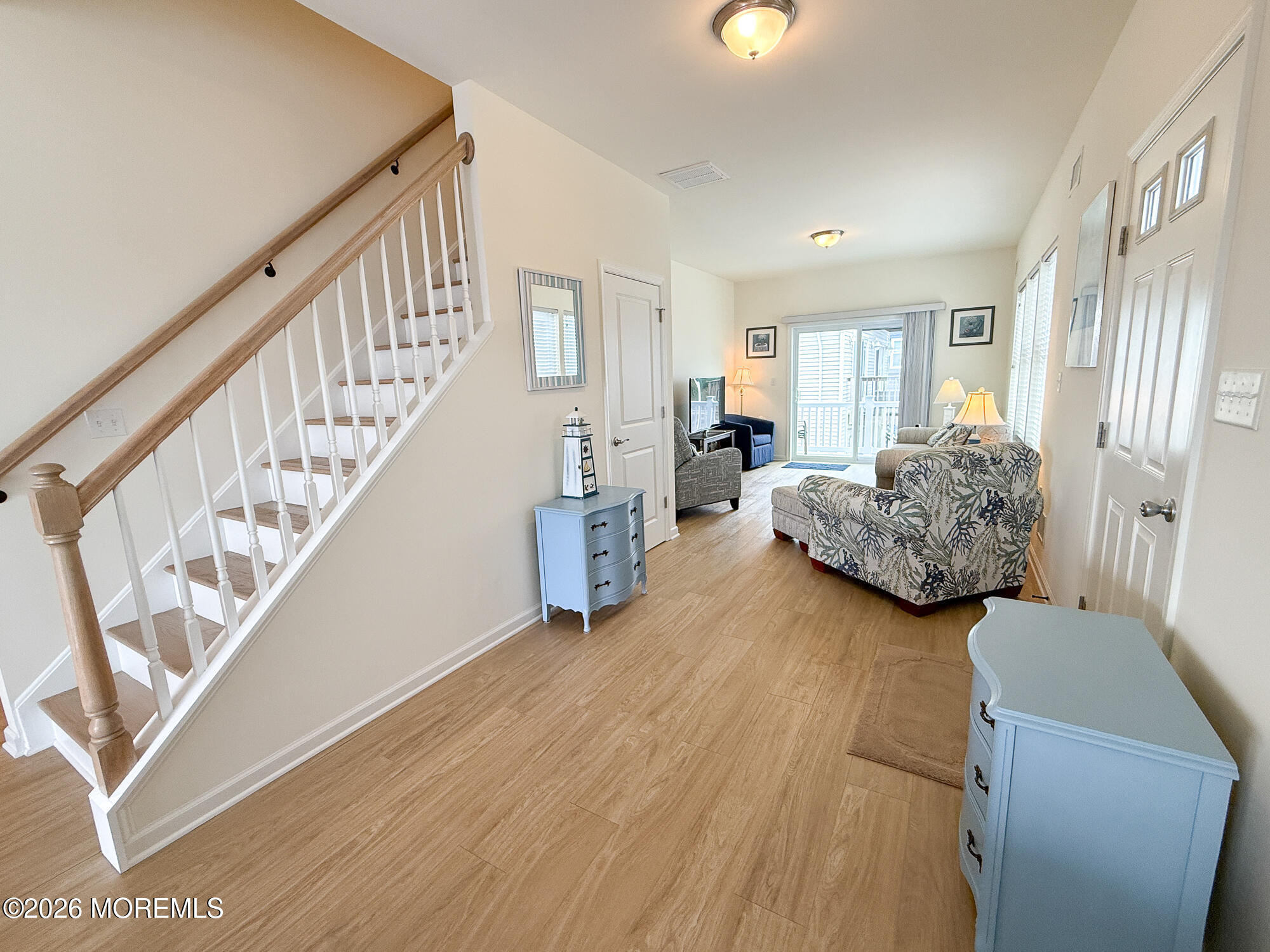 Furnished entry hall with a staircase opening into a living room and sliding glass doors.