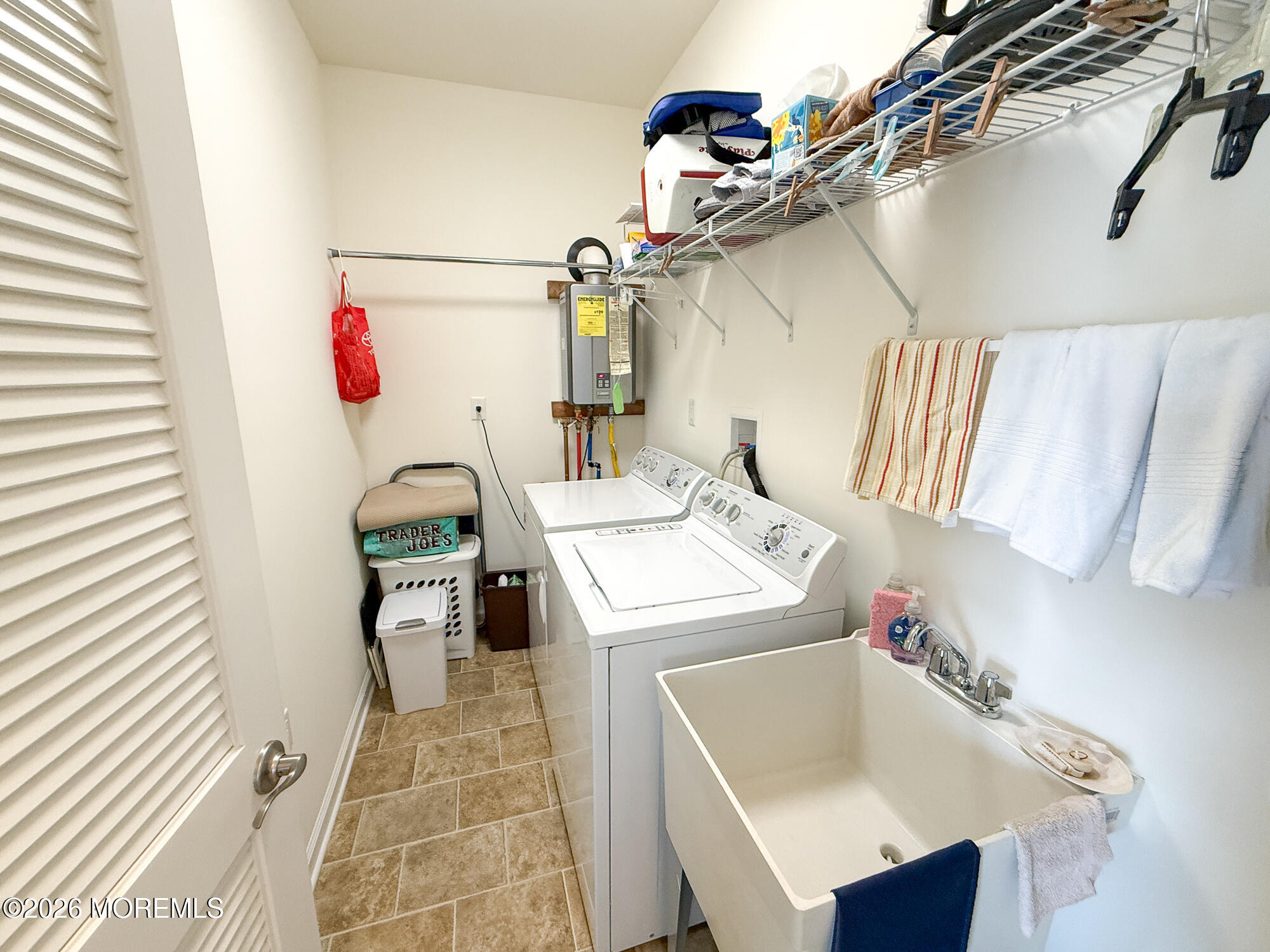 Laundry room with washer and dryer, deep utility sink, and overhead wire shelving.