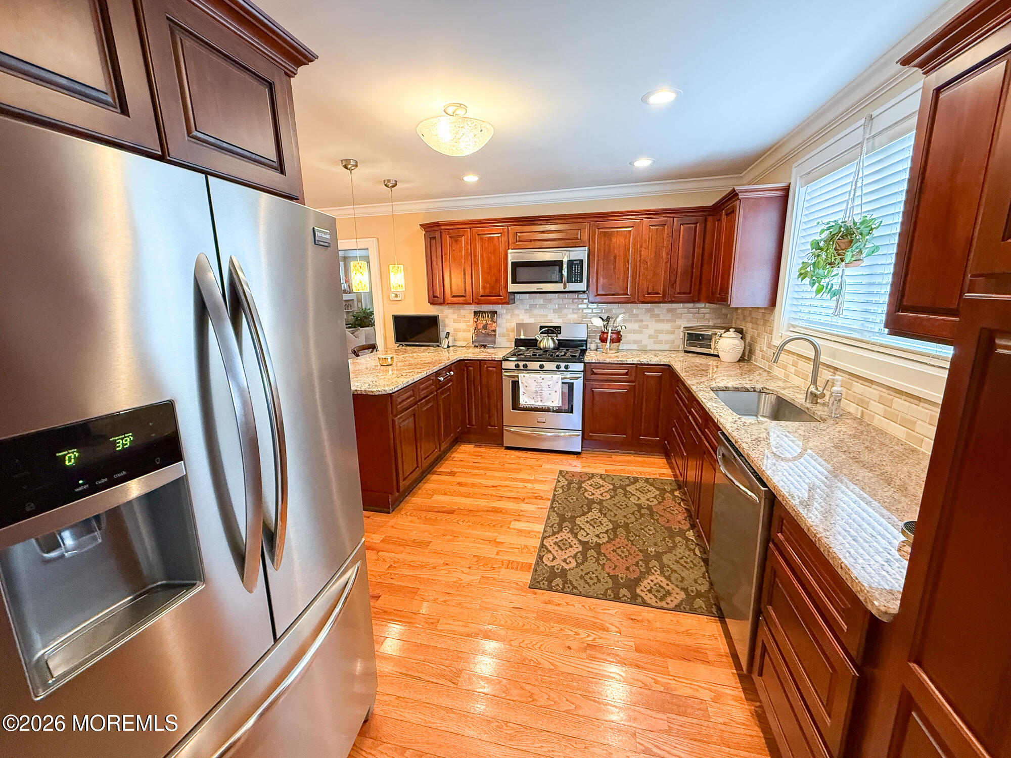 Kitchen with cherry cabinets, granite counters, stainless steel appliances, and a sink beneath a window.