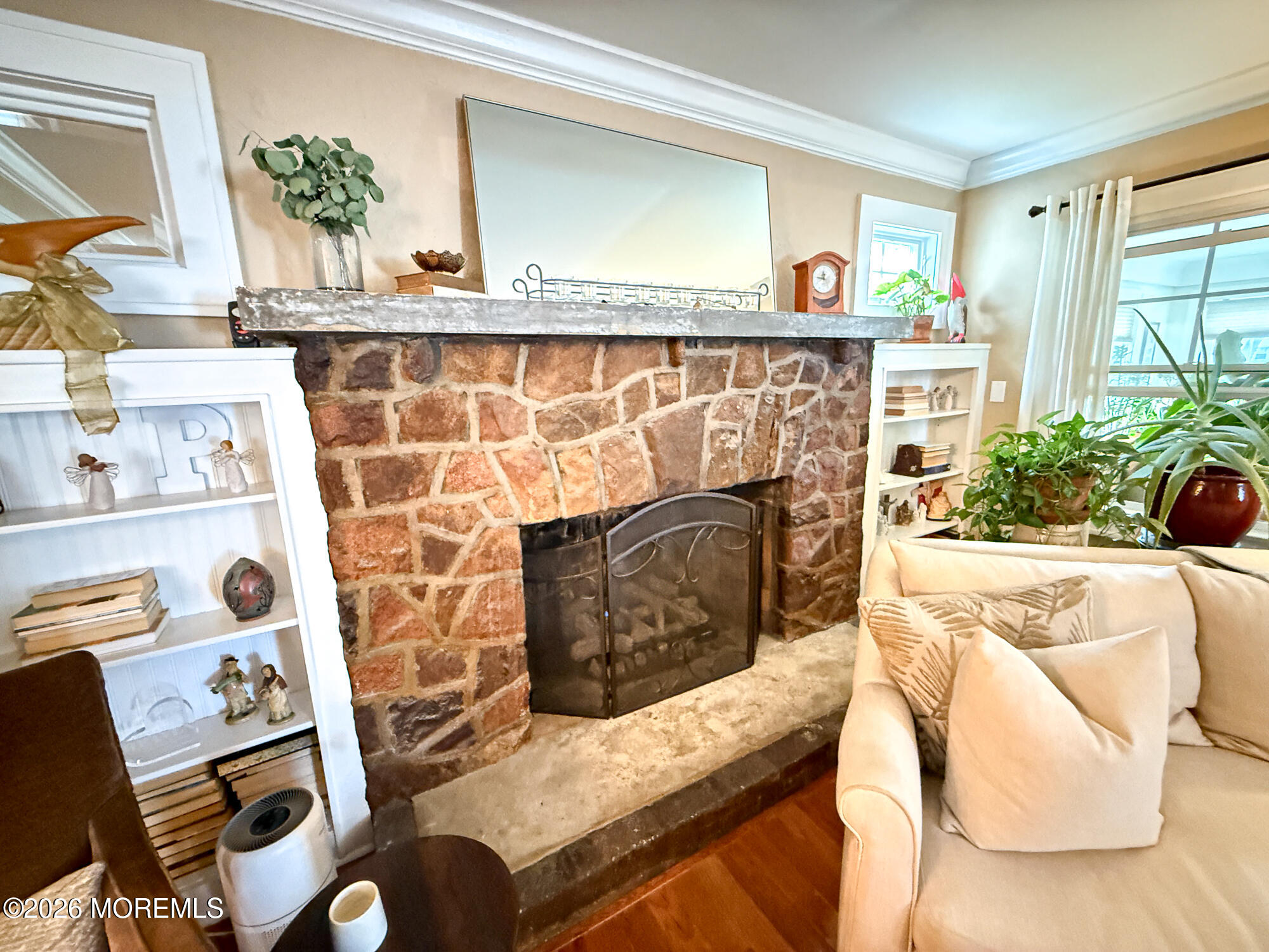 Living room with a broad stone fireplace, built-in shelves, and a cream sofa.