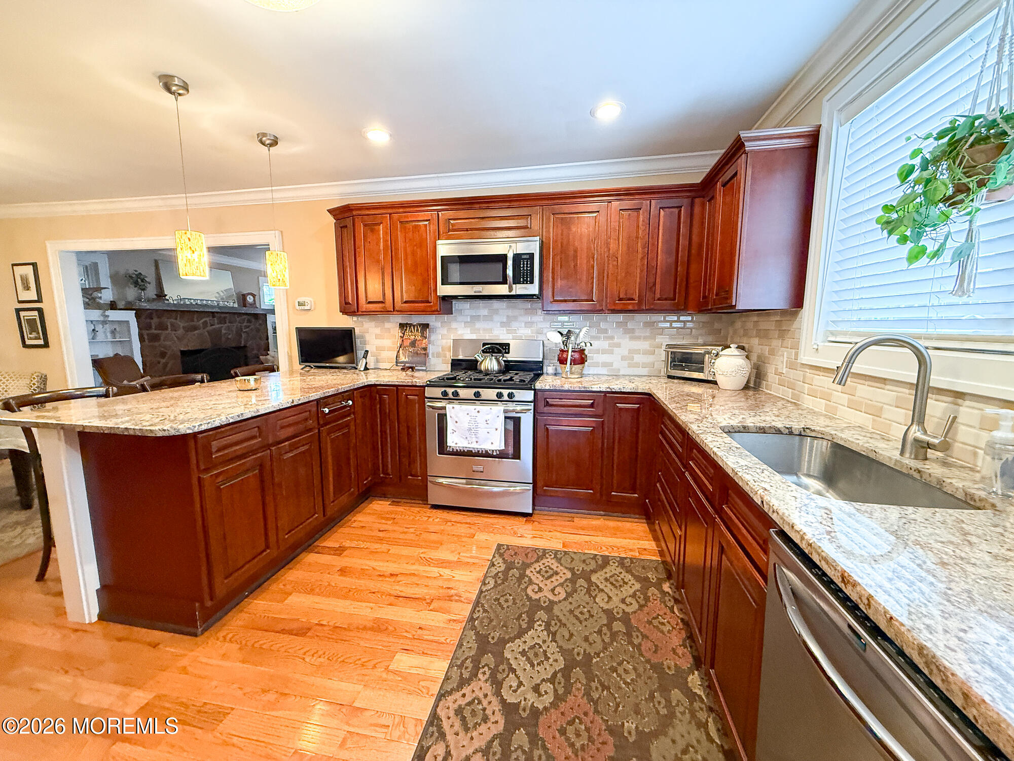 Kitchen with cherry cabinets, granite counters, stainless steel appliances, and a window above the sink.