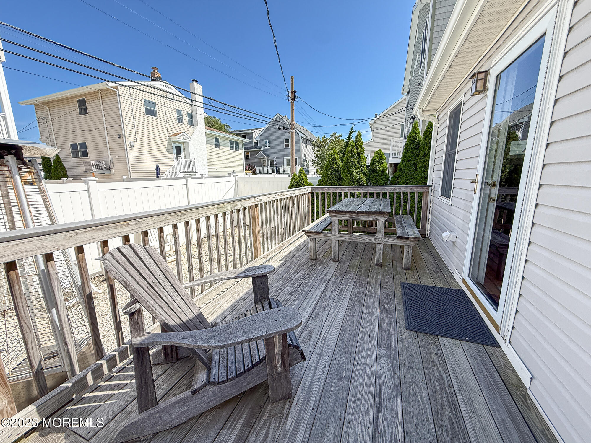 Wood deck with an Adirondack chair and picnic table beside a sliding glass door.