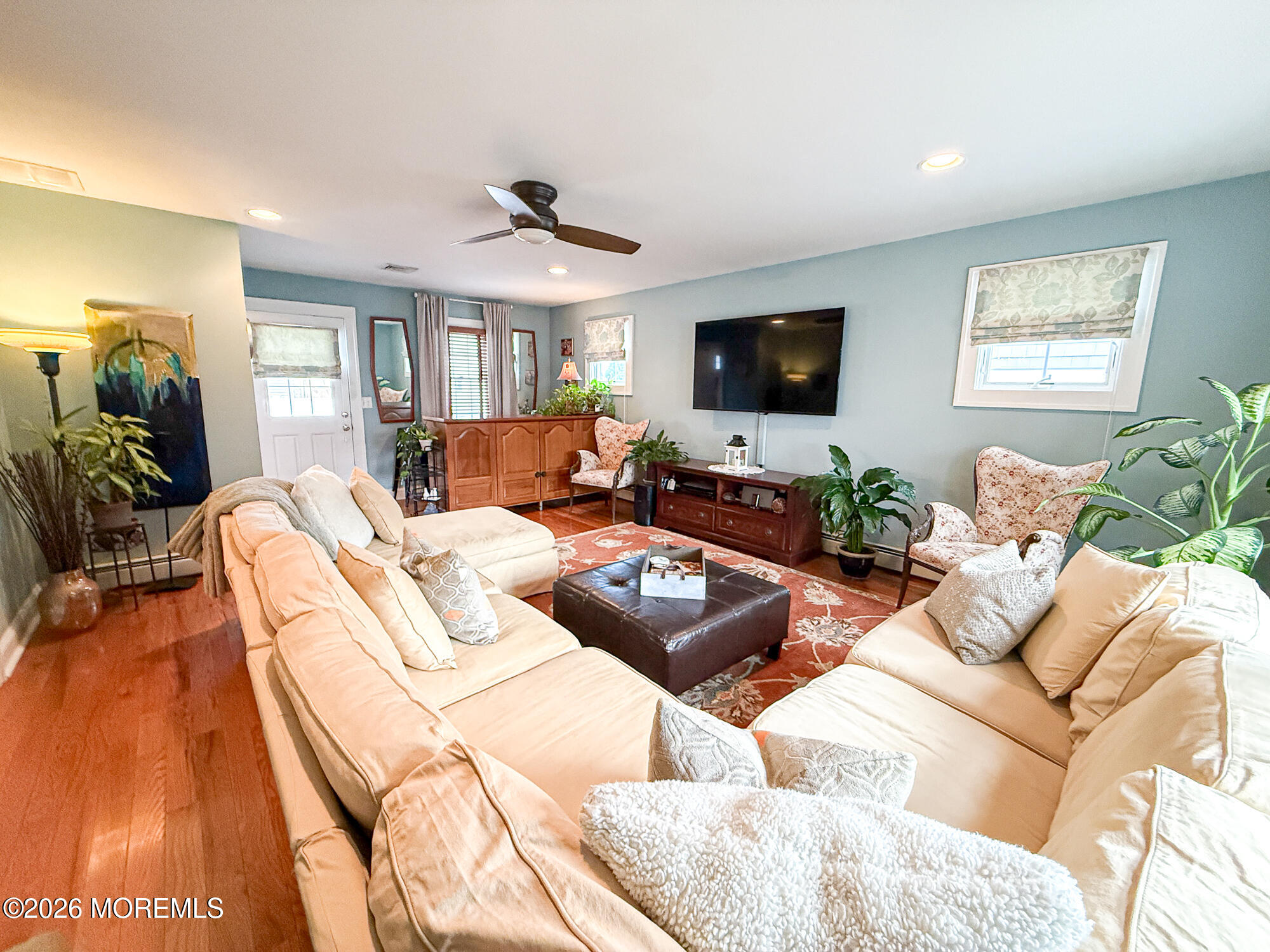 Furnished living room with cream sofas, a patterned rug, and a wall-mounted television.