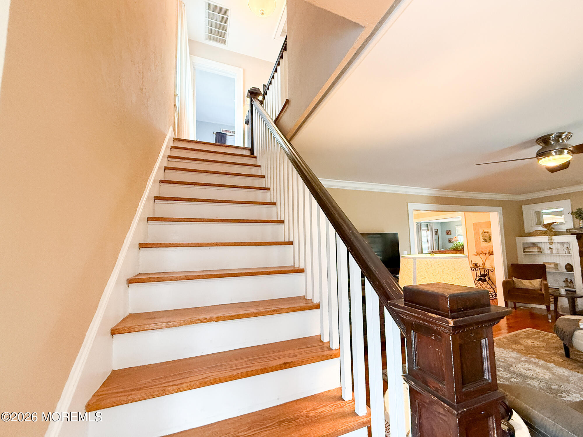 Wood-tread staircase with white balusters beside a furnished living room.