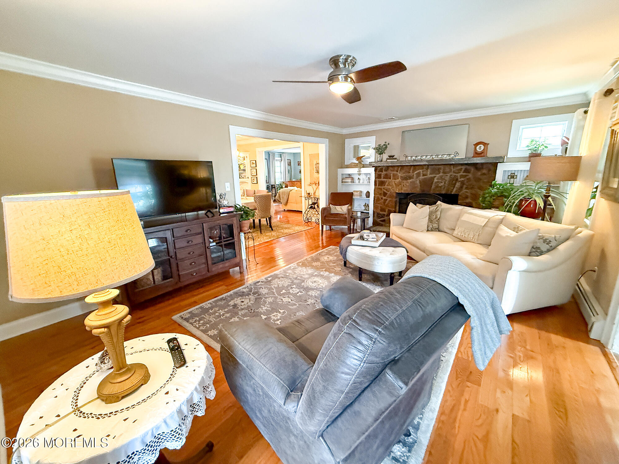 Living room with a stone fireplace, cream sectional, gray recliner, and hardwood floors.