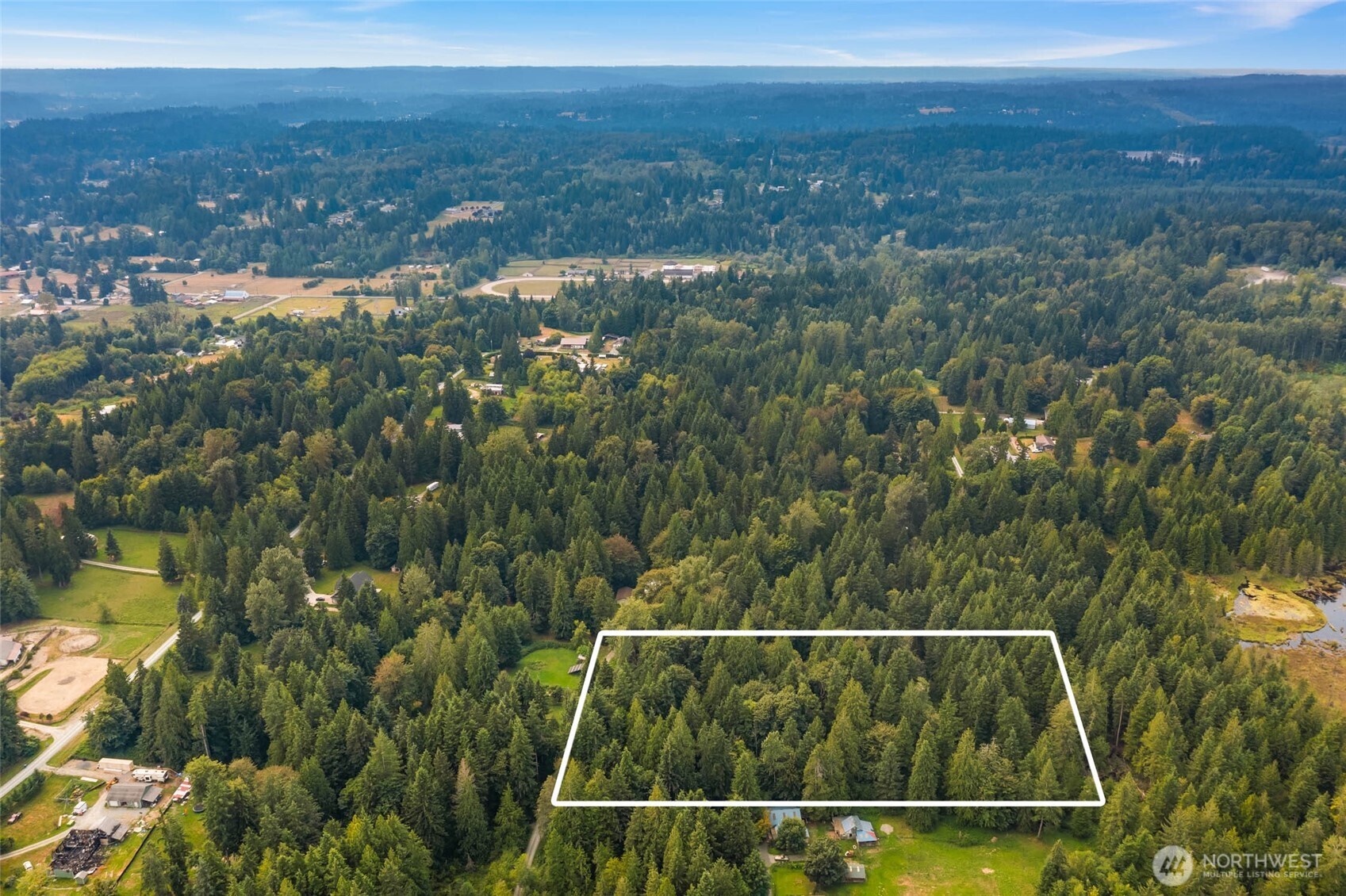 Aerial view of a wooded lot outlined in white, surrounded by forest and rural properties.
