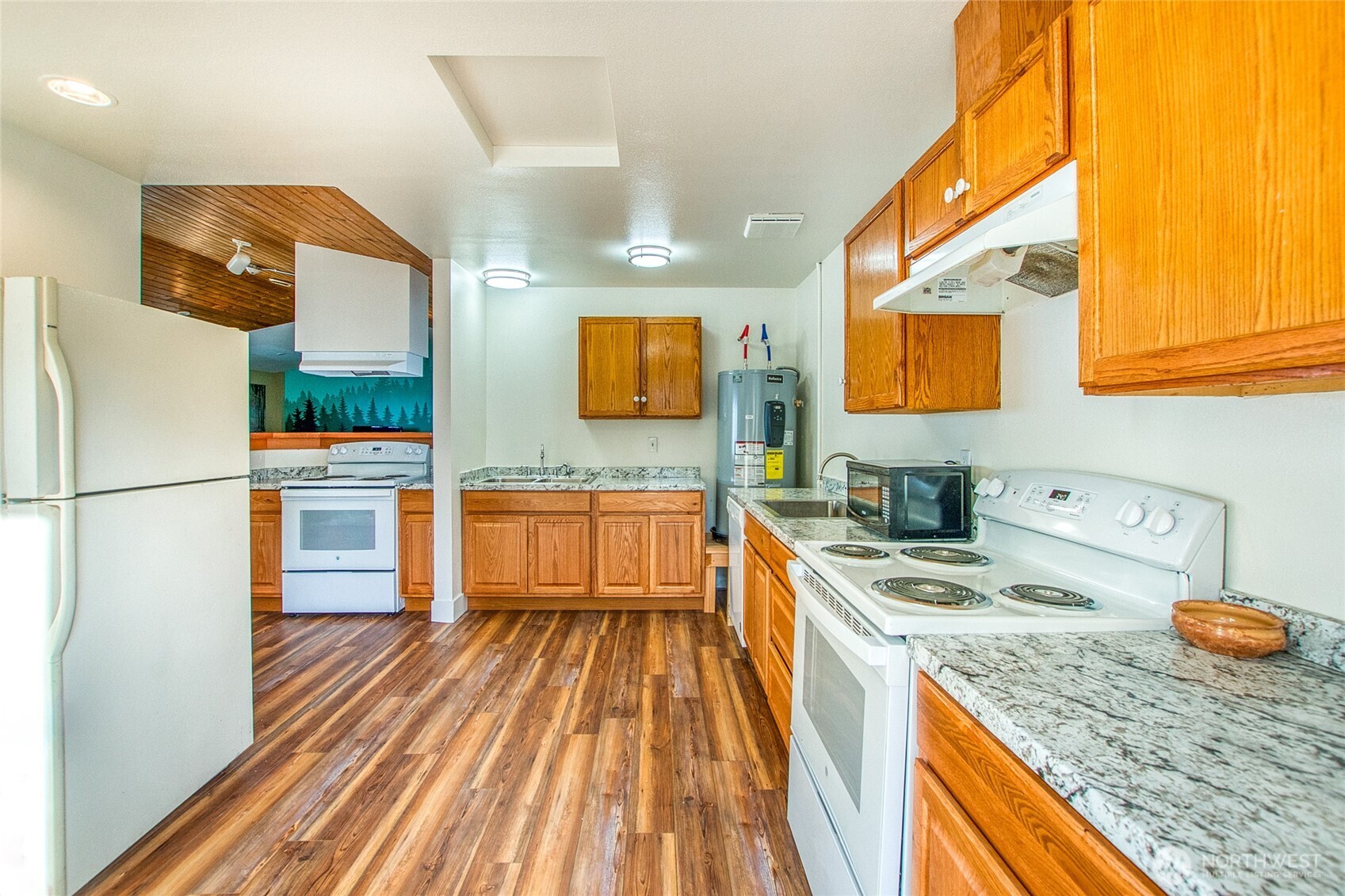 Kitchen with honey-colored wood cabinets, granite countertops, and wood-look flooring.