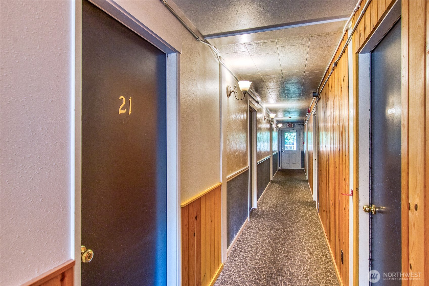 Interior hallway with wood-paneled walls, carpeted floor, and a door numbered 21.