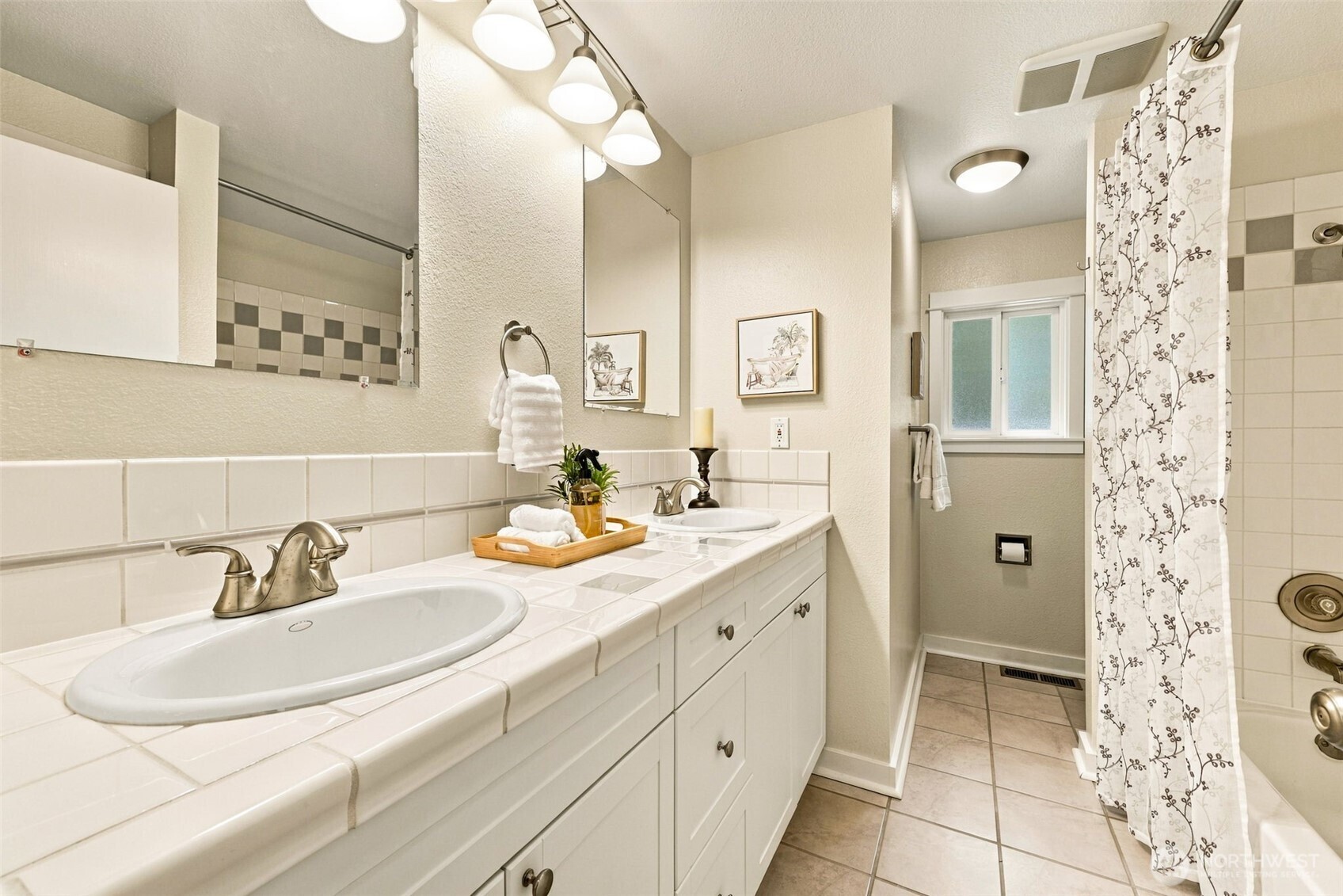 Bathroom with a long double-sink tiled vanity and a patterned shower curtain.
