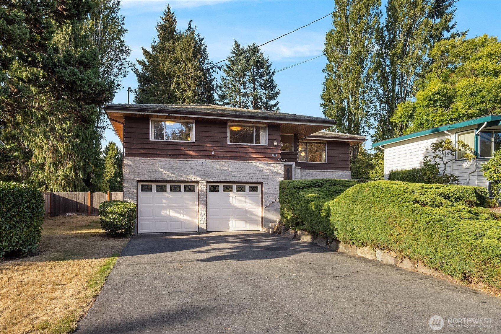 Split-level home with a stone lower facade, two garage doors, and a landscaped driveway.