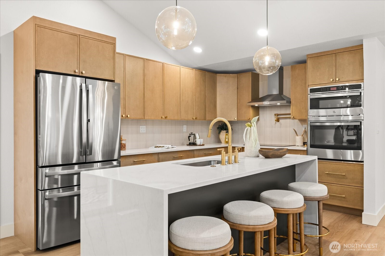 Modern kitchen with wood cabinets, stainless appliances, and a large island with seating.