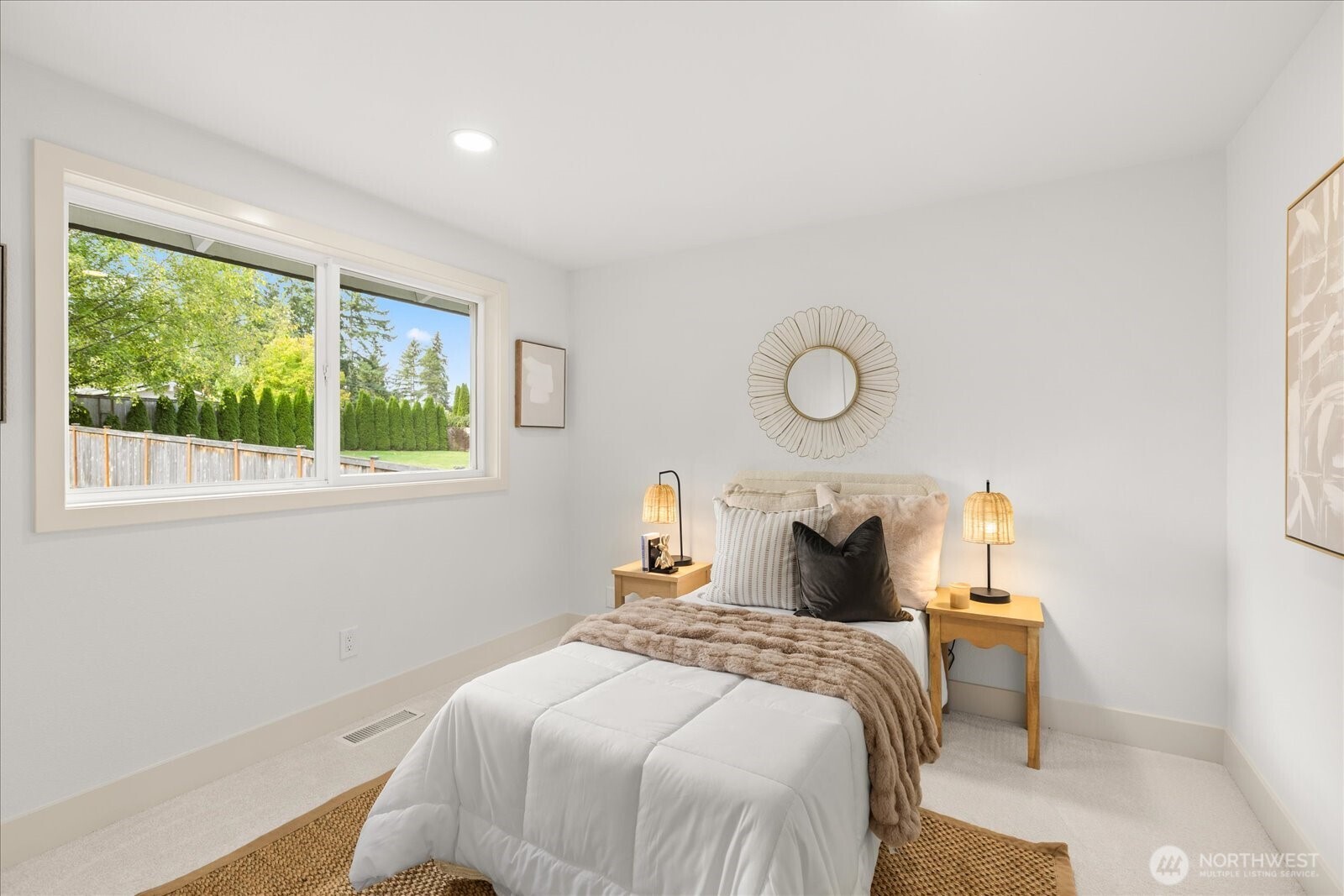 Staged bedroom with a white bed and large window overlooking a green yard.