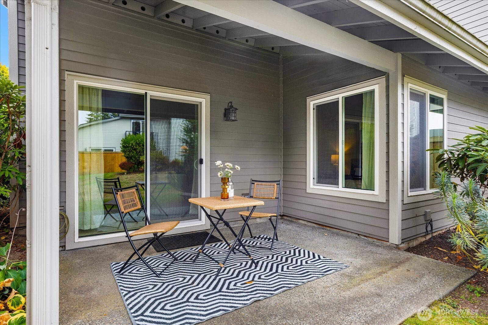 Covered patio with a small table and chairs on a black-and-white patterned rug.
