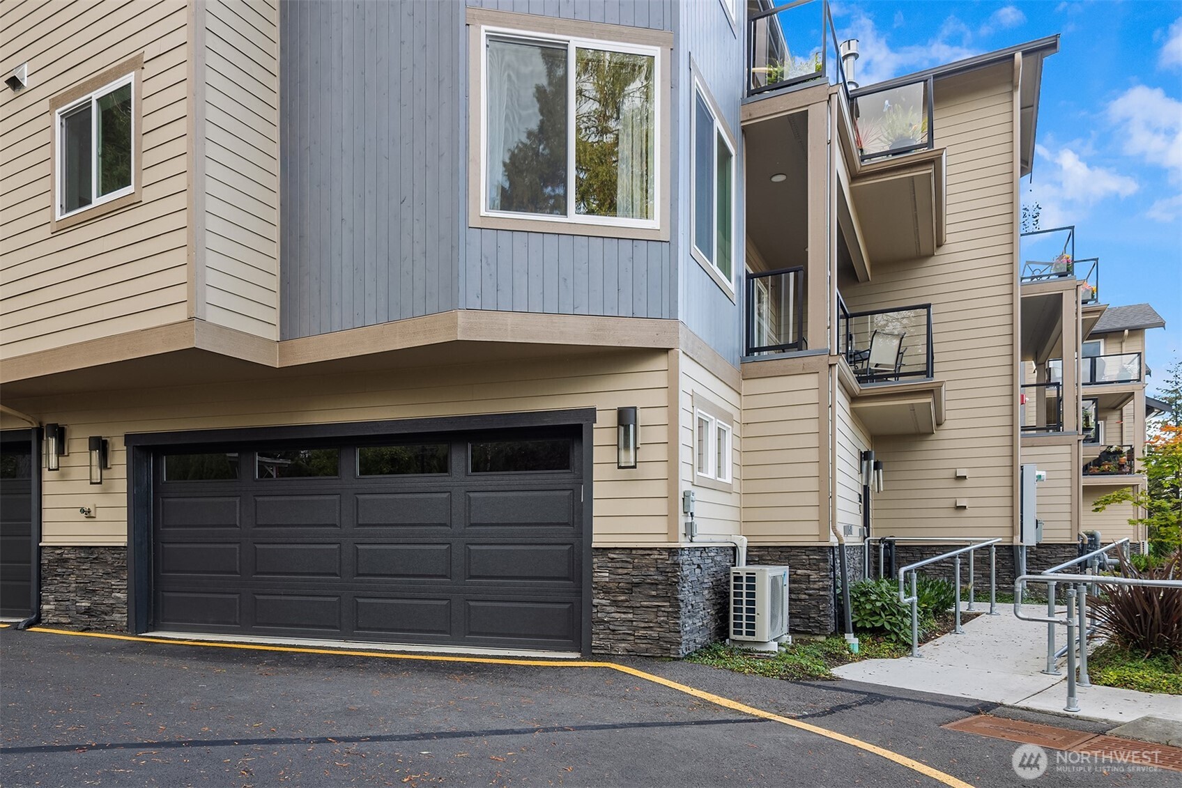 Multi-unit building exterior with a dark garage door and balconies.
