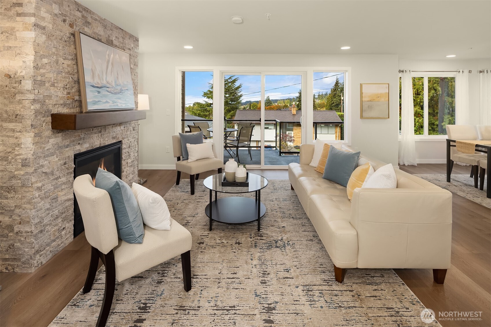 Staged living room with a stone fireplace, cream seating, and sliding doors to a balcony.