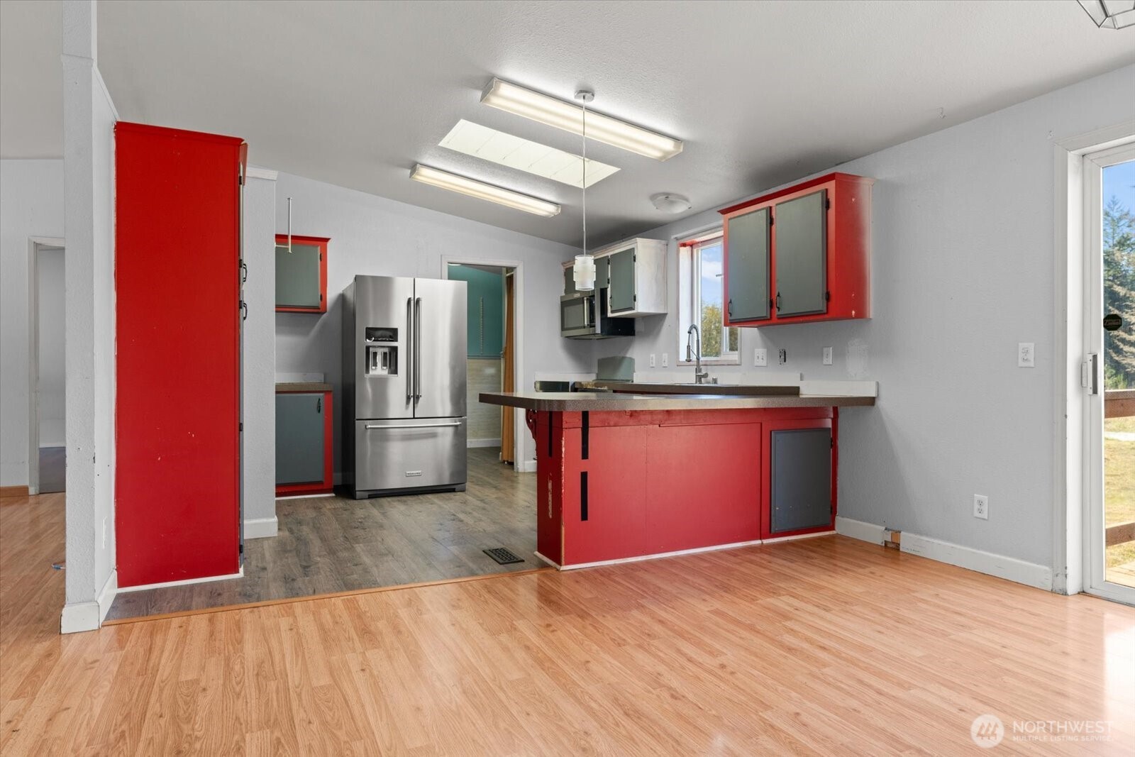 Kitchen with bold red cabinets, a peninsula, and stainless steel refrigerator.