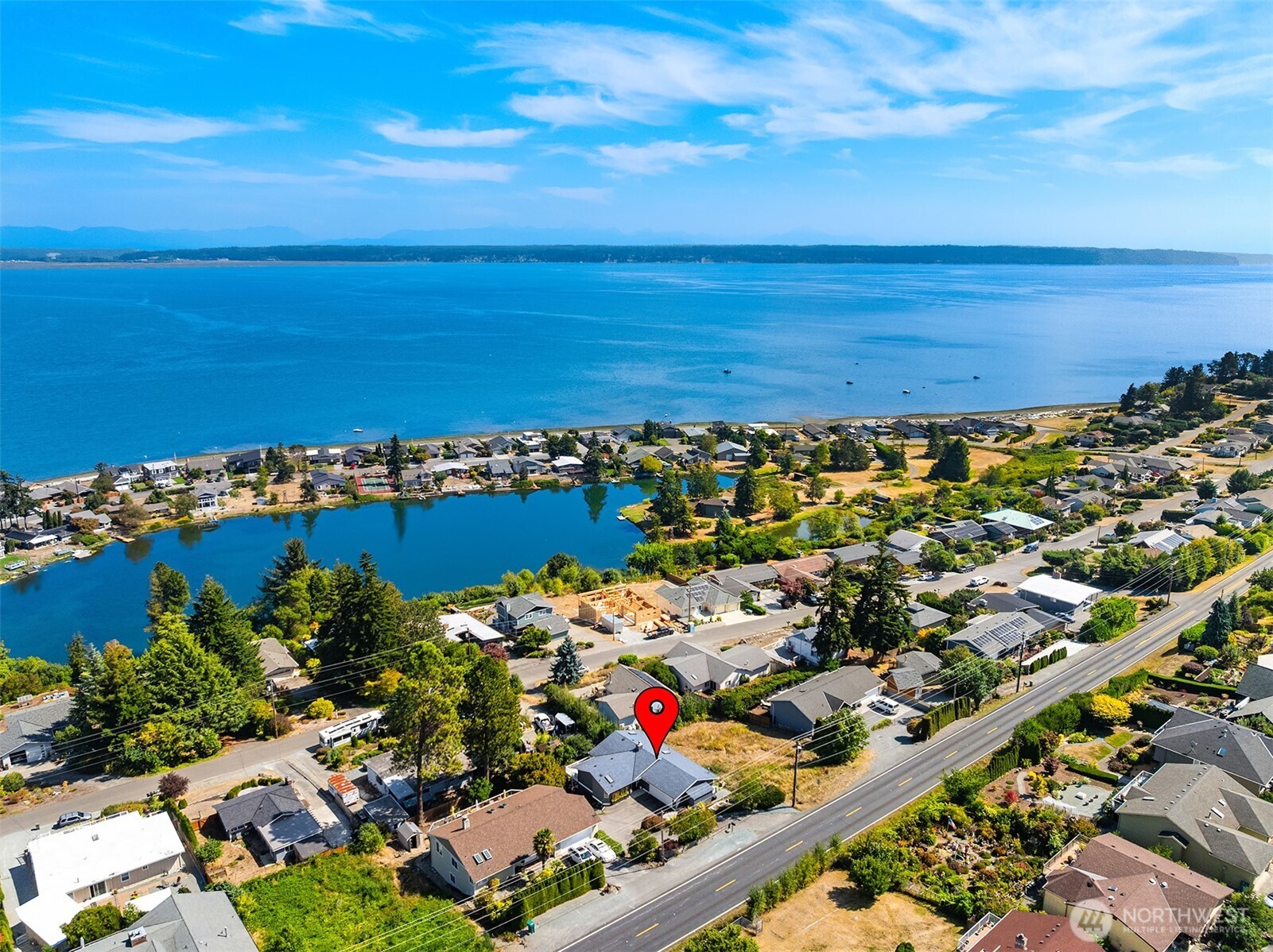 Aerial view of the marked home between a lagoon and waterfront, with expansive water views.