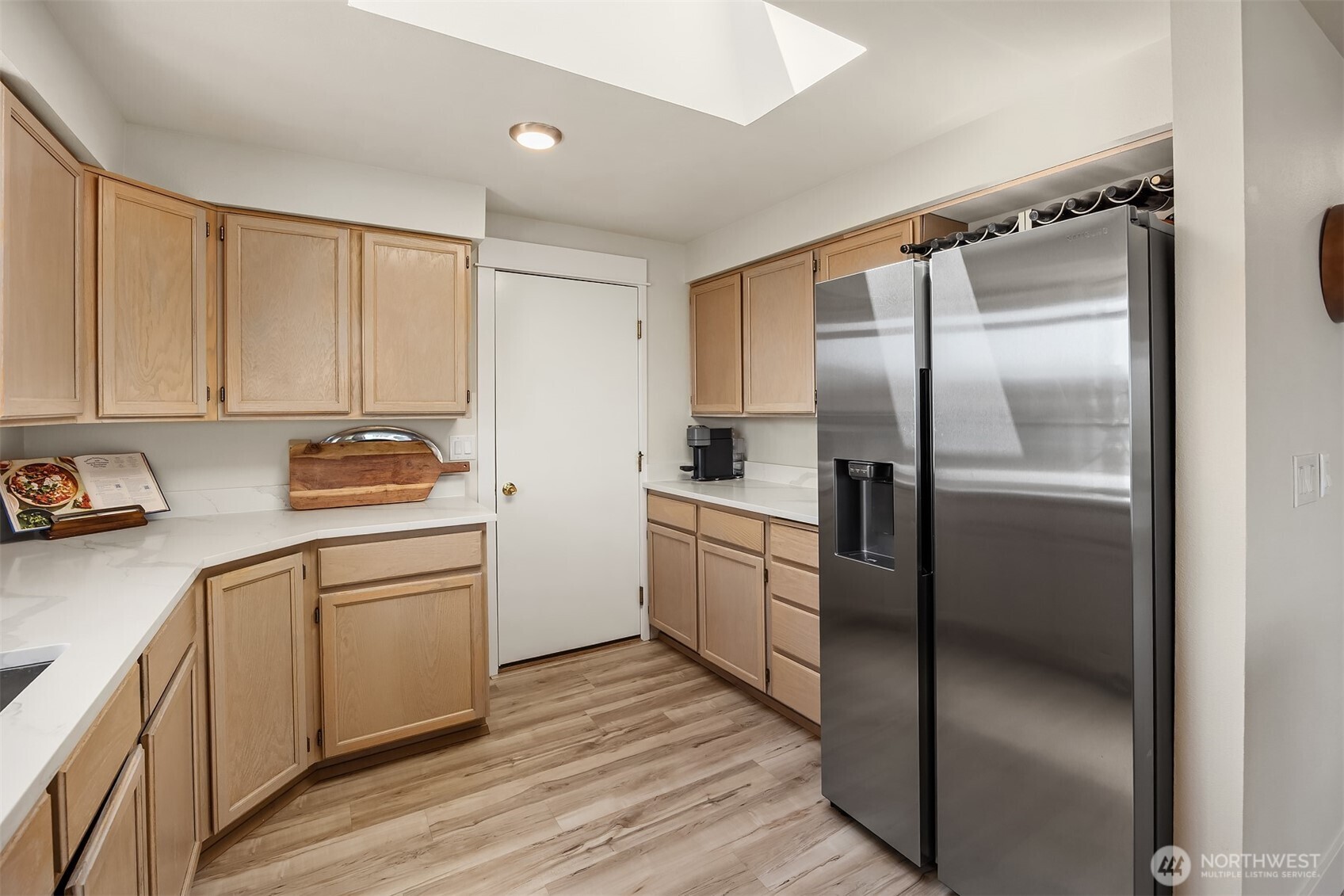 Kitchen with light wood cabinets, white countertops, and a stainless steel side-by-side refrigerator.