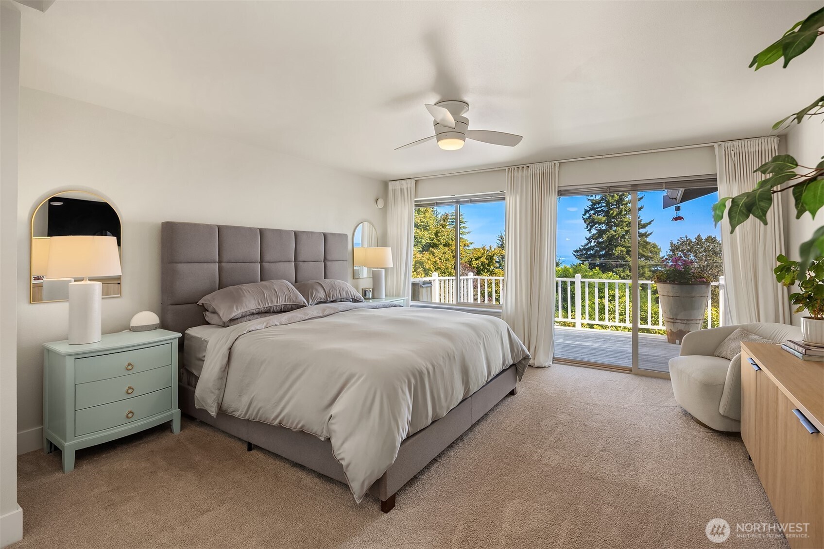 Furnished bedroom with sliding doors opening onto a deck and water view.