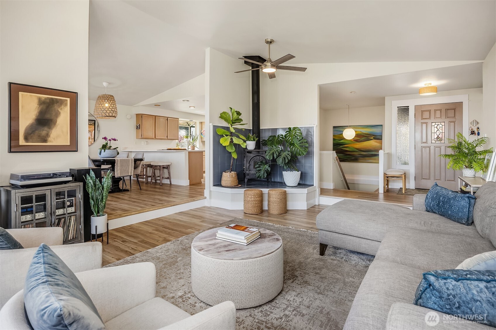 Open-plan living room with a tiled fireplace, black wood stove, and dining area.