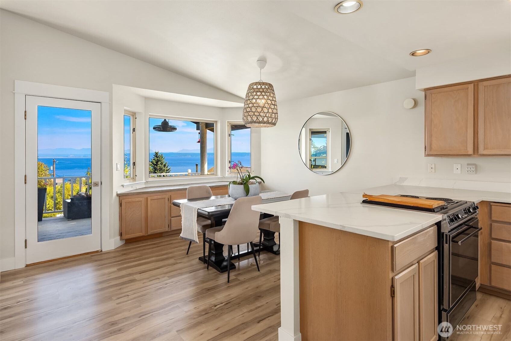 Kitchen and dining area with a large island and windows overlooking blue water.