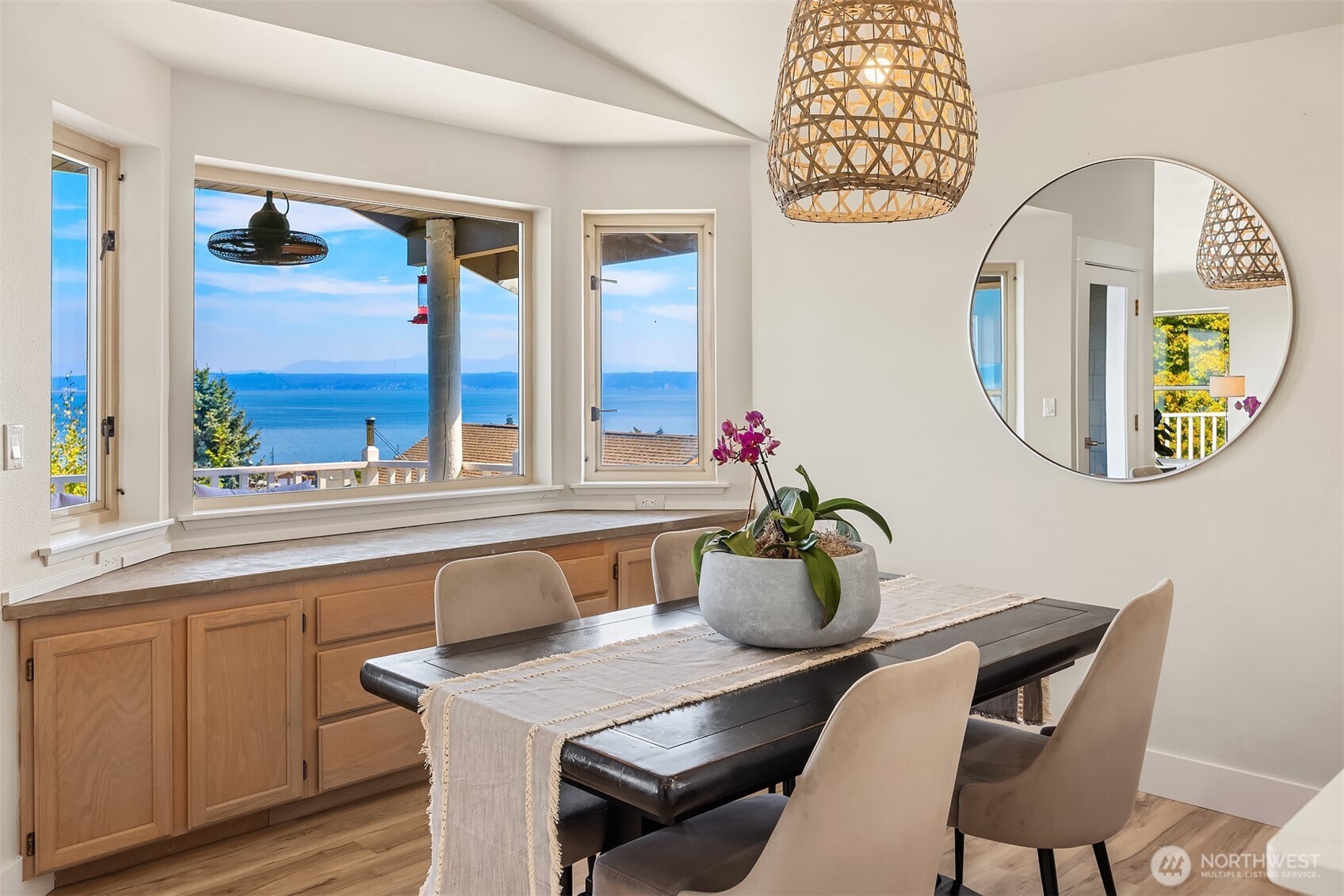 Dining area with large windows overlooking blue water and distant land.