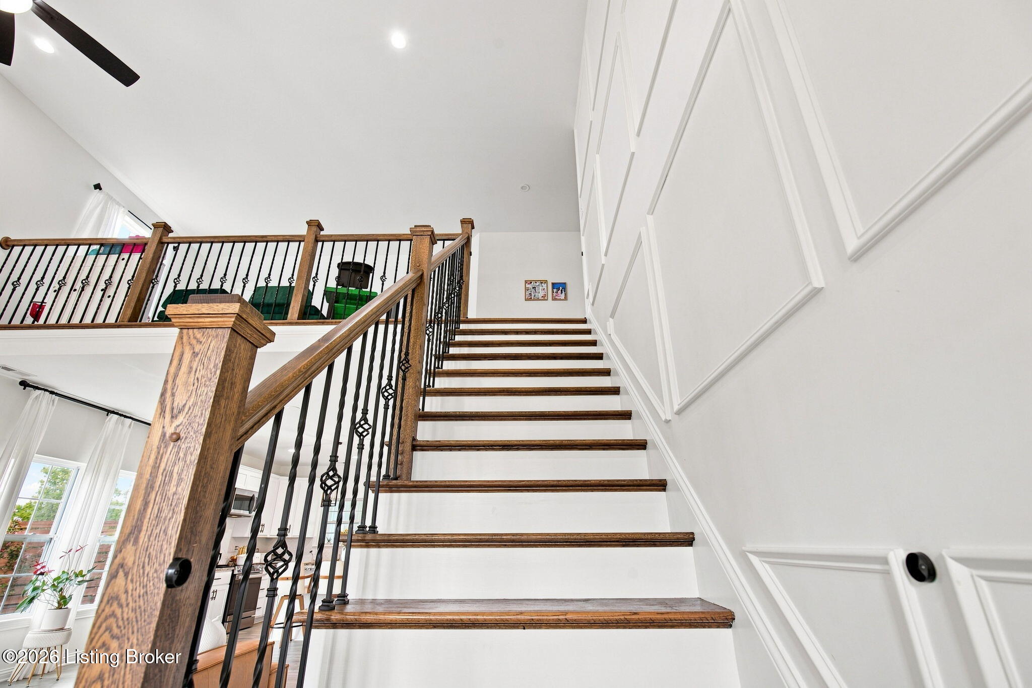 Staircase with dark wood treads, black iron balusters, and decorative white wall paneling.