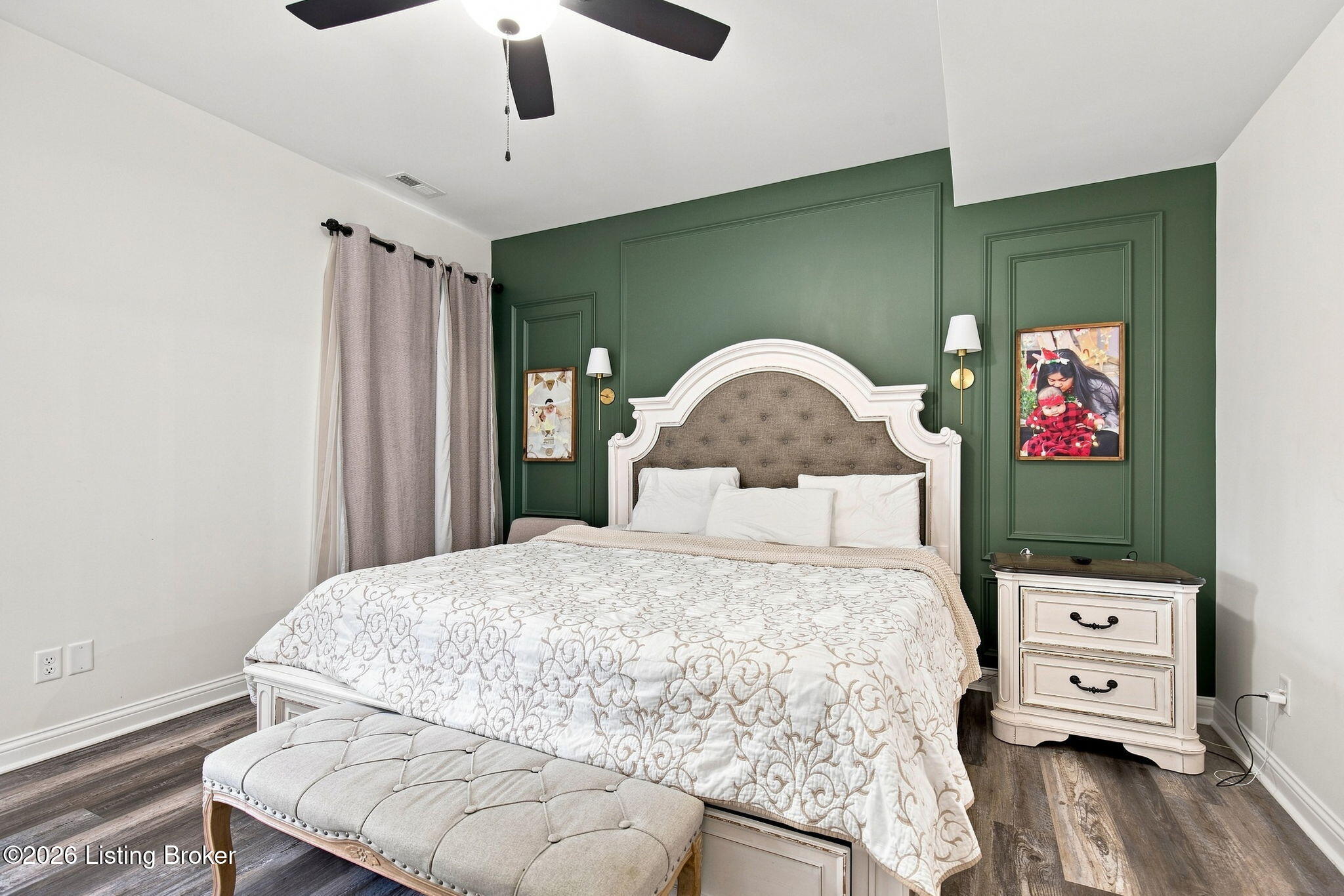 Bedroom with a green paneled accent wall, ornate white bed, and upholstered bench.
