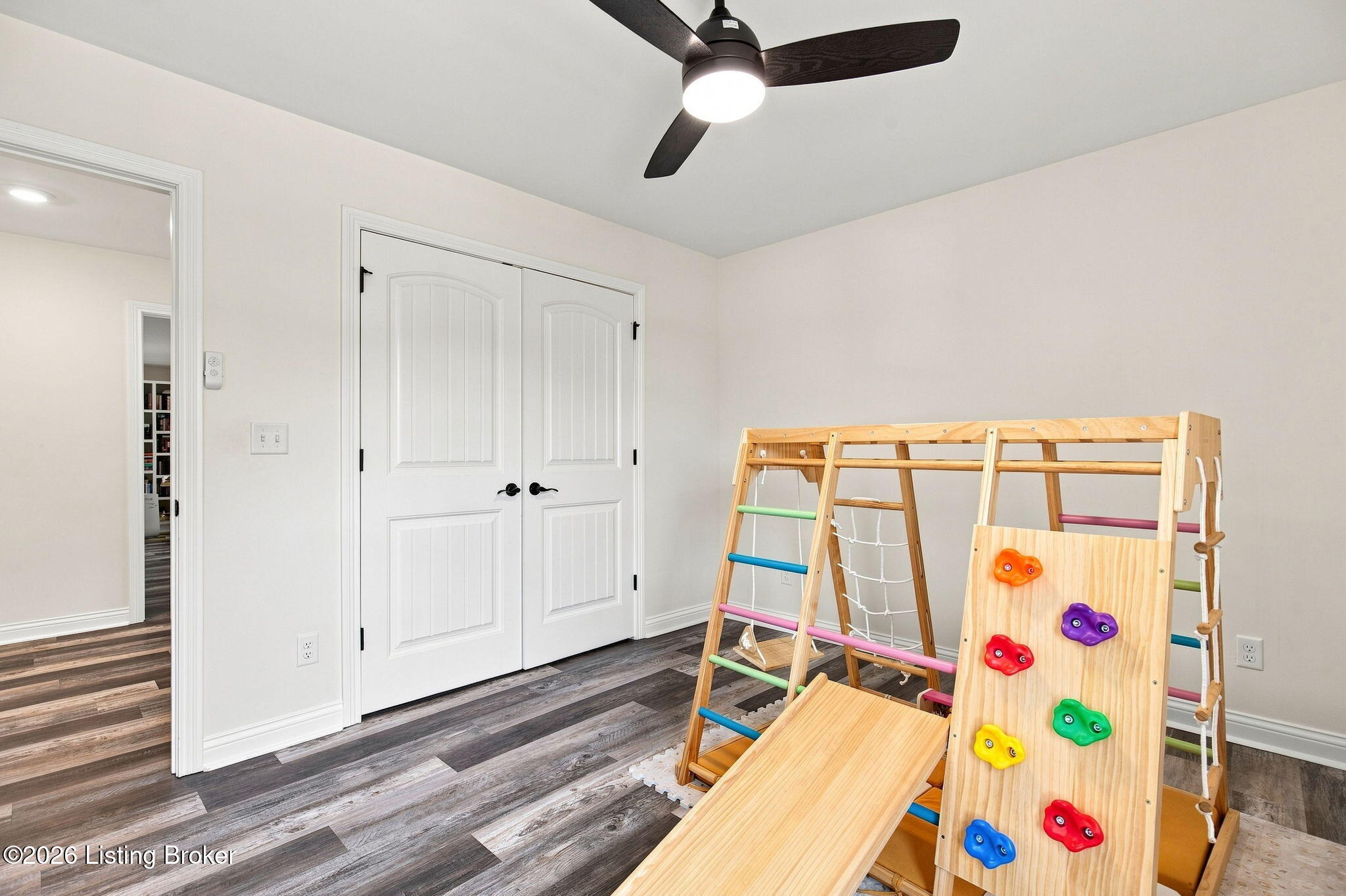 Playroom with a wooden climbing structure, slide, and colorful climbing holds.