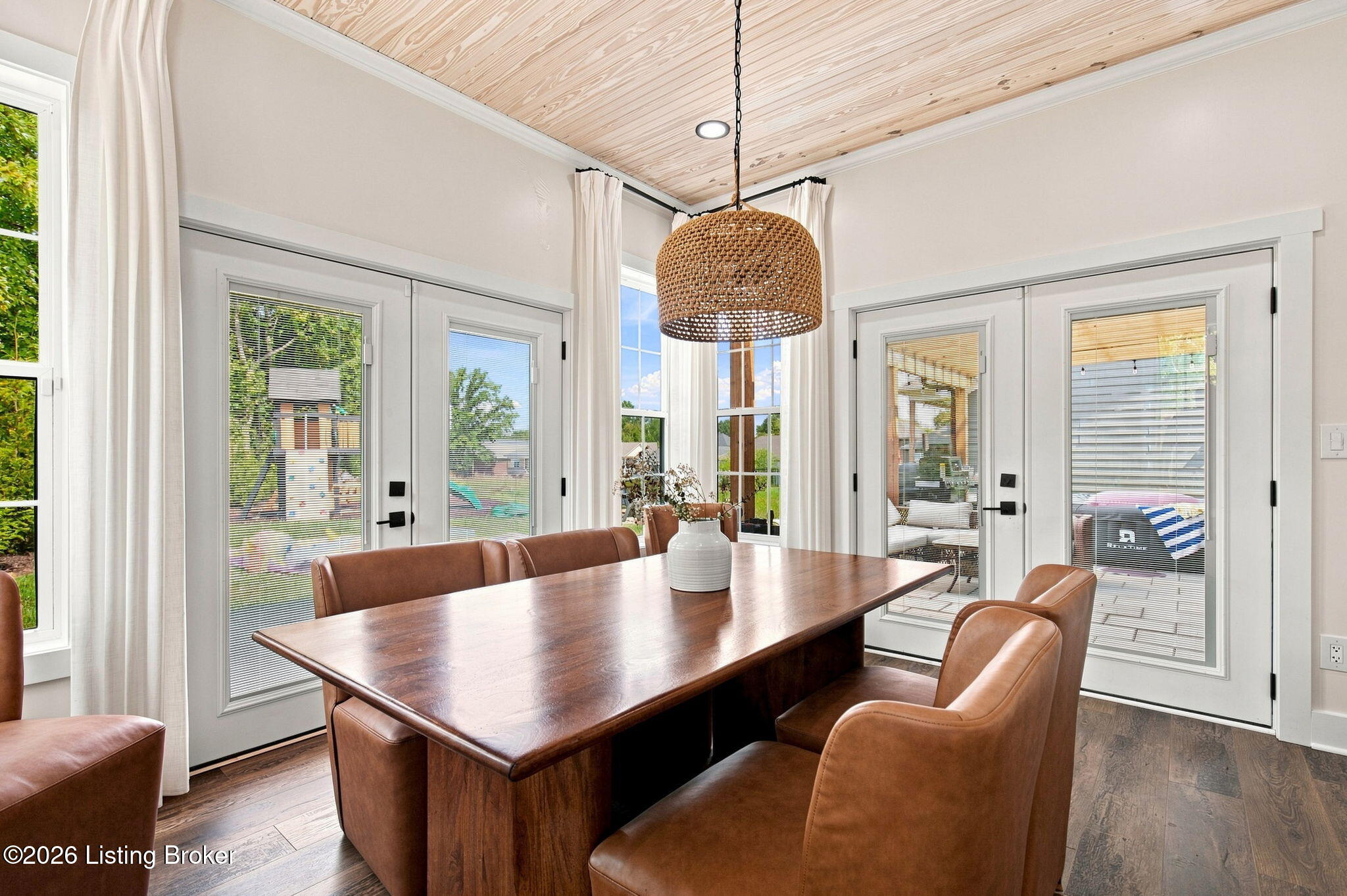 Dining room with a wood-plank ceiling, leather chairs, and glass doors to the patio.