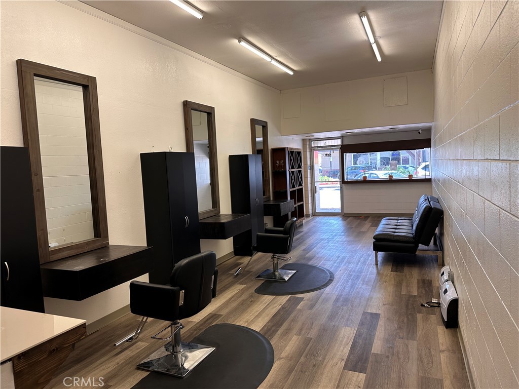 Salon interior with styling chairs and mirrors, plus a waiting sofa by the storefront window.