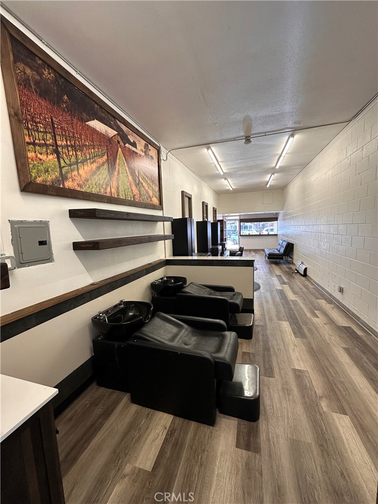 Hair salon with black shampoo stations, reclining chairs, and a long wood-look floor.