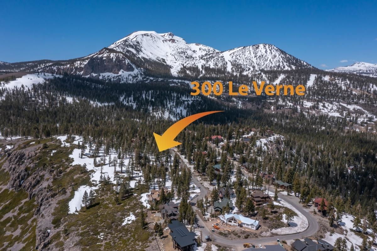 Aerial view of 300 Le Verne St beneath snow-covered mountains, marked by an orange arrow.
