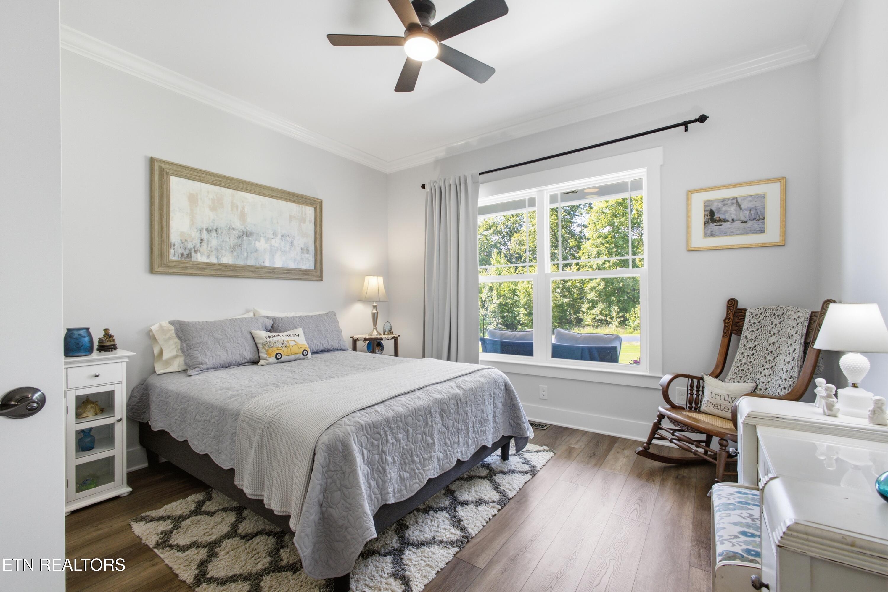 Bedroom with a gray quilted bed, large window, and wooden rocking chair.