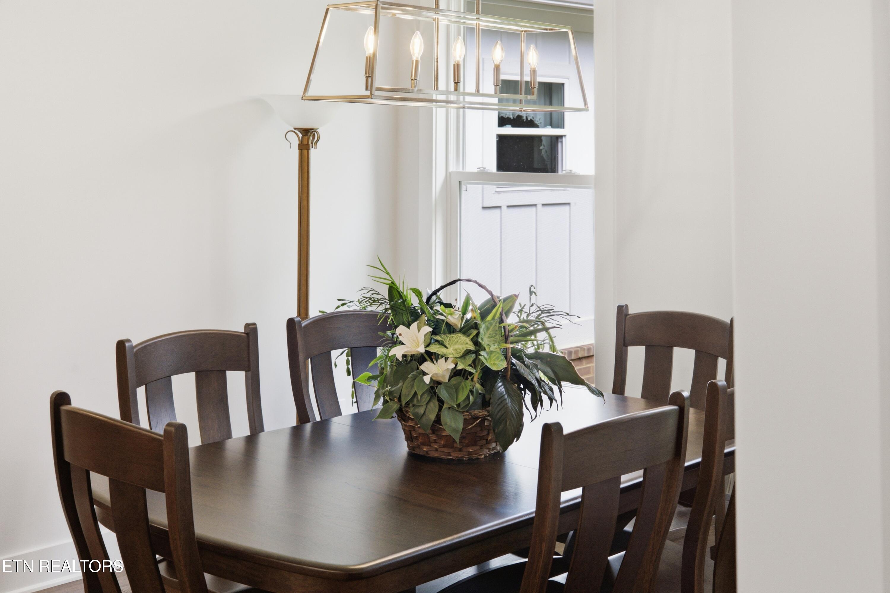 Dining room with a dark wood table and chairs, floral centerpiece, and brass chandelier.