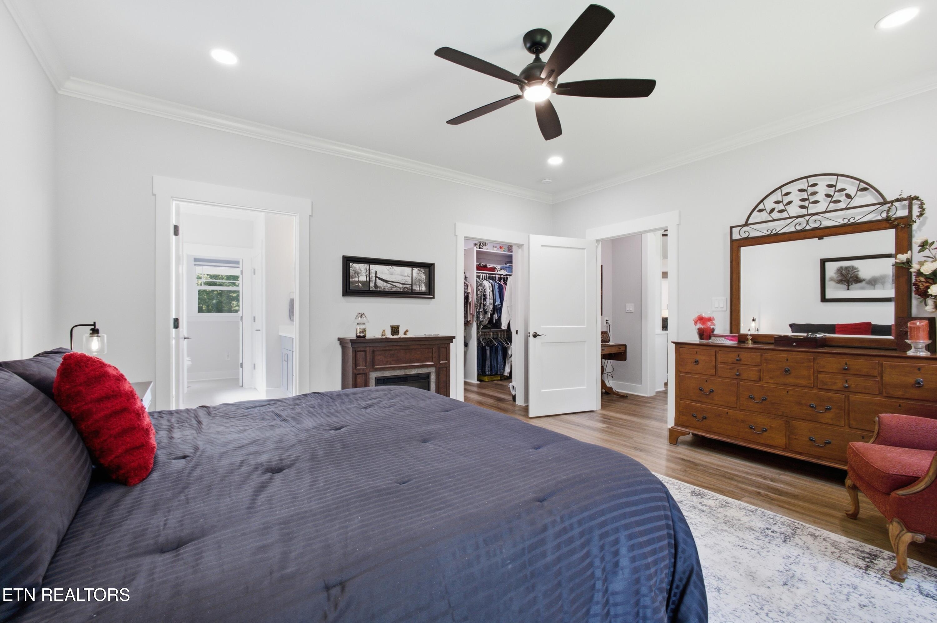Bedroom with dark blue bedding, a wooden dresser and mirror, and an open closet.