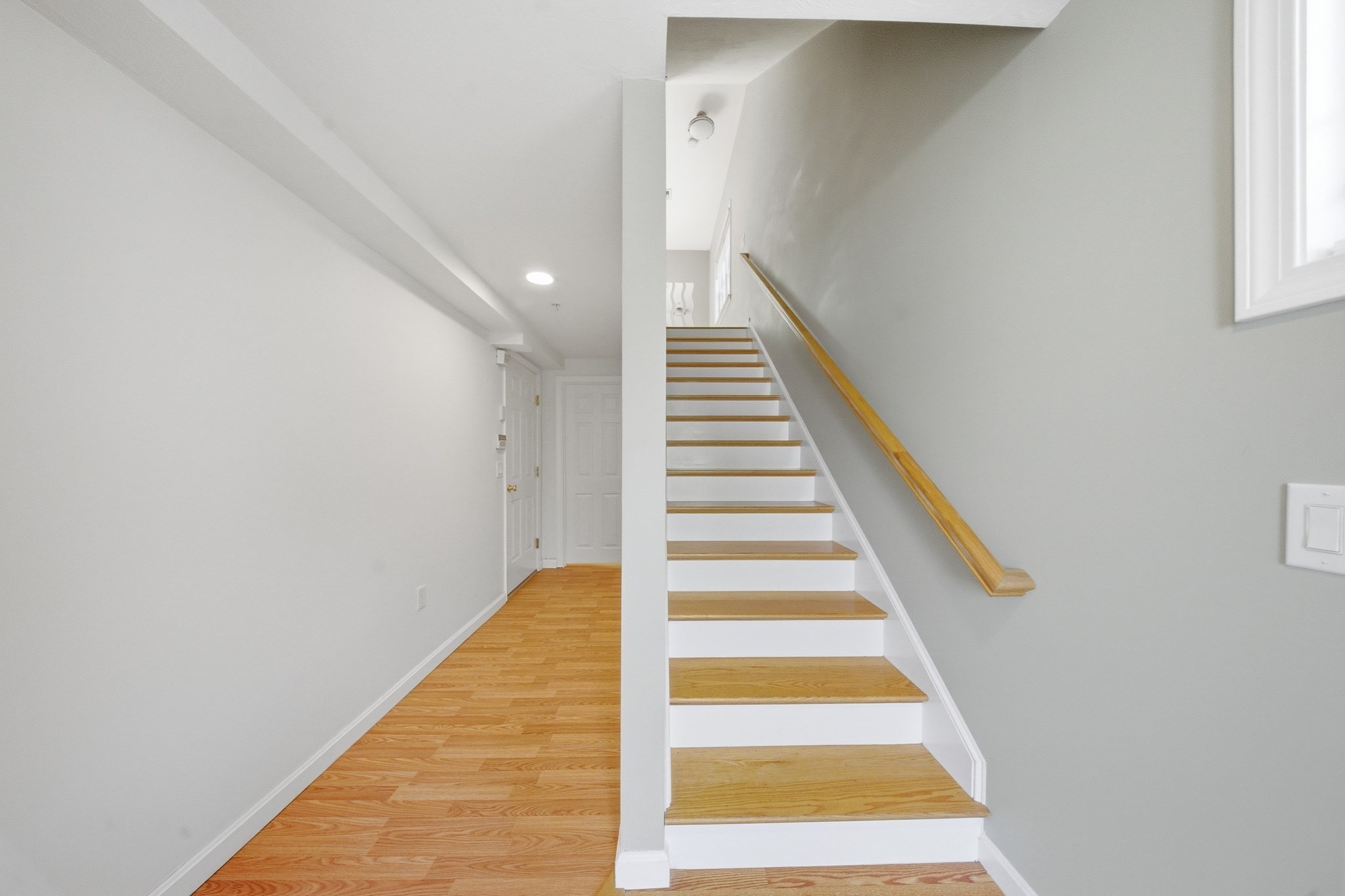 Entry hall with hardwood floors and a staircase with natural wood treads and handrail.