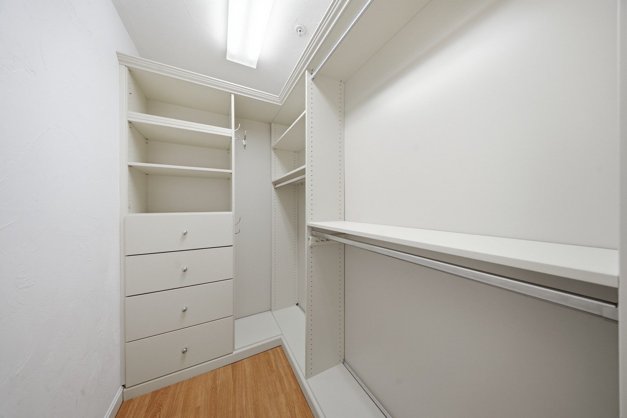 Walk-in closet with built-in drawers, shelves, and hanging rods.