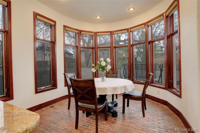 Sunroom with a round dining table, brick floor, and curved wall of tall windows.